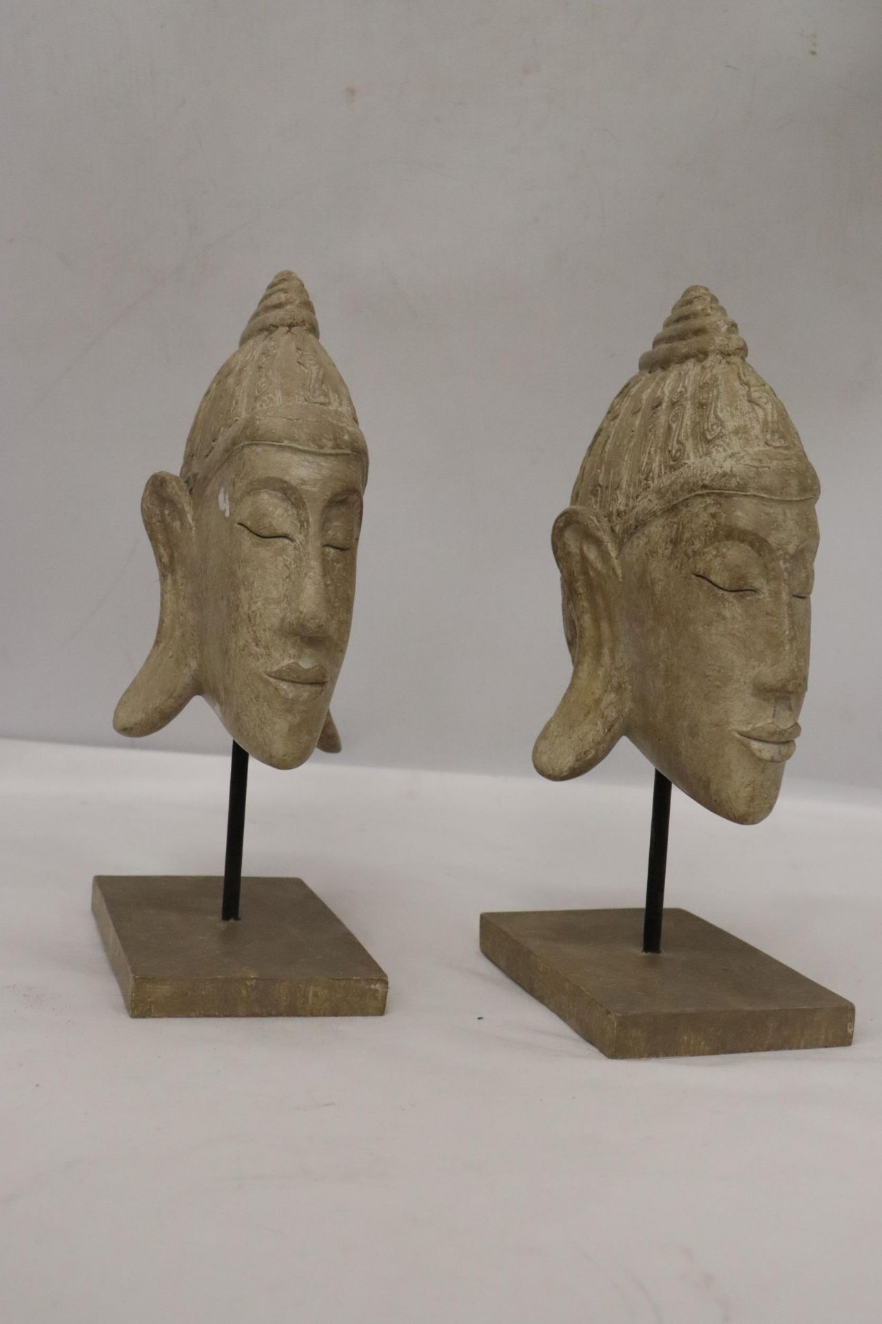 TWO BUDDAH HEADS ON STANDS, HEIGHT 27CM