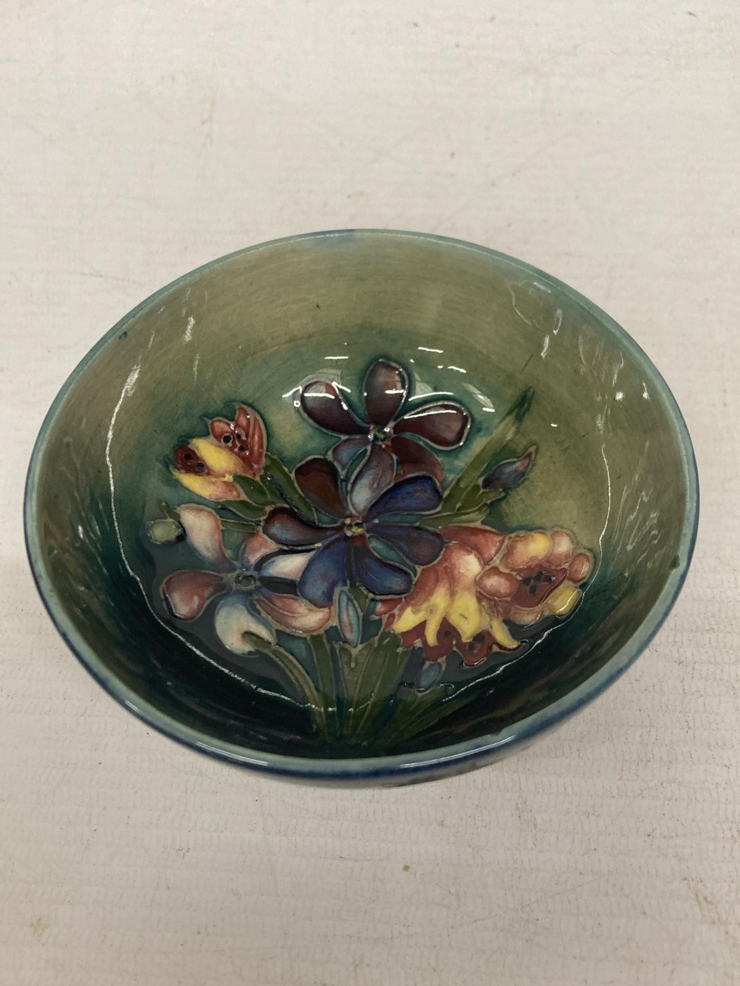 A MOORCROFT ENGLAND SPRING FLOWERS SMALL BOWL (TINY NIBBLE TO THE RIM)