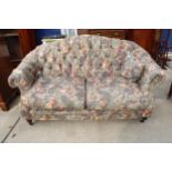 A VICTORIAN STYLE TWO SEATER BUTTON BACK SETTEE ON TURNED FRONT LEGS