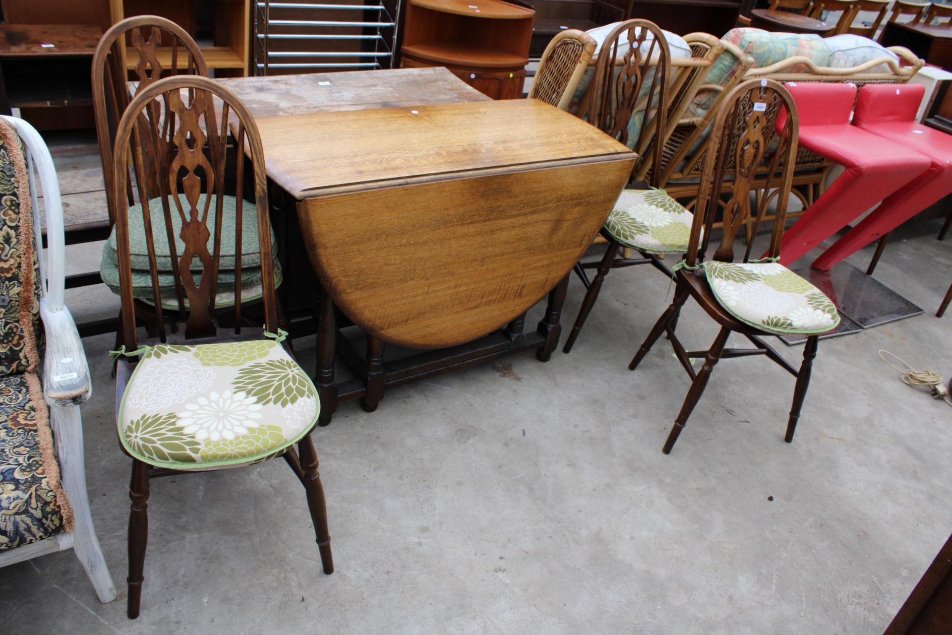 AN OVAL OAK GATELEG DINING TABLE AND FOUR ERCOL STYLE WINDSOR CHAIRS