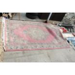 A LARGE PINK PATTERNED FRINGED RUG