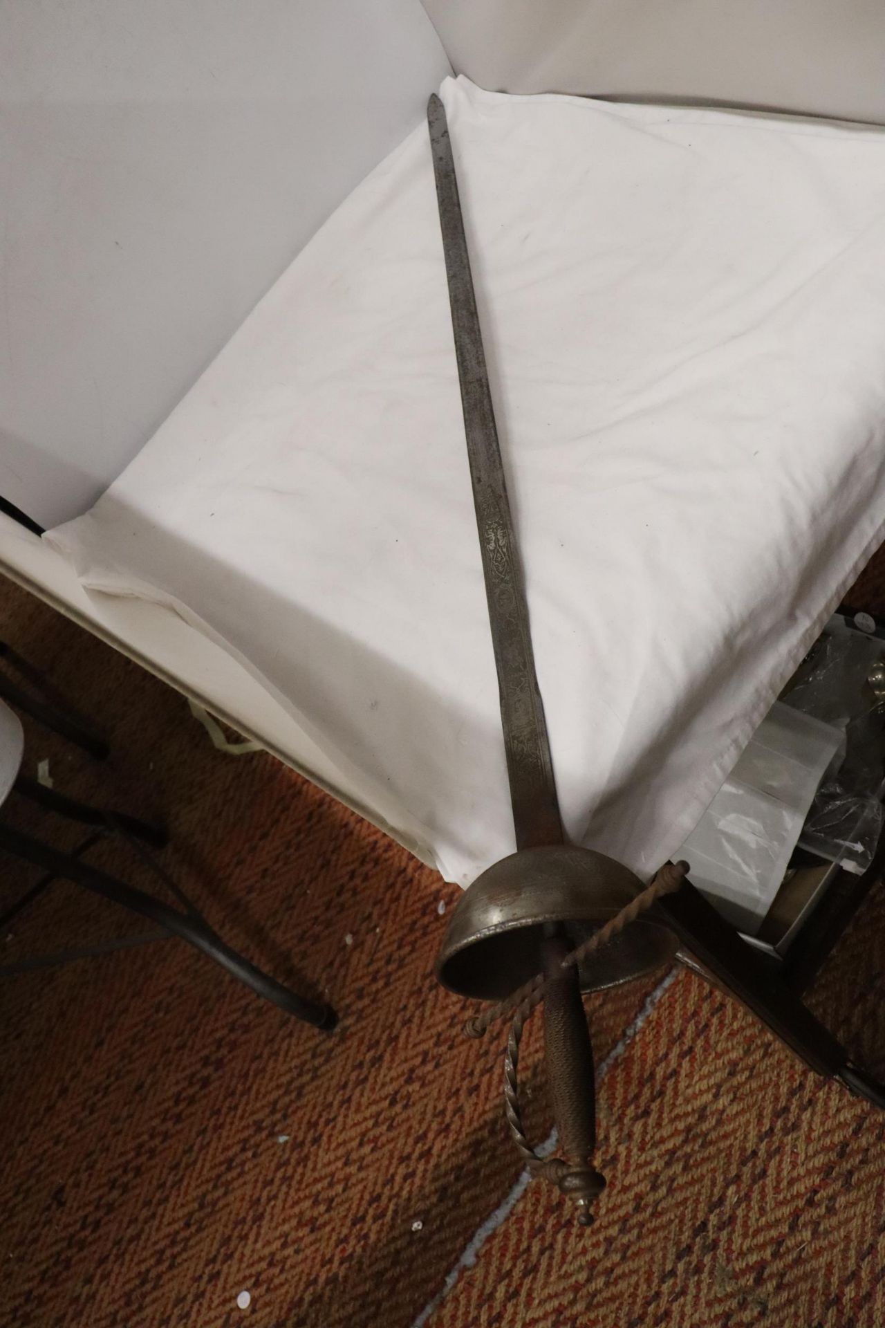 A VINTAGE SWORD WITH A BASKET HILT AND ENGRAVING TO THE TOP OF THE BLADE
