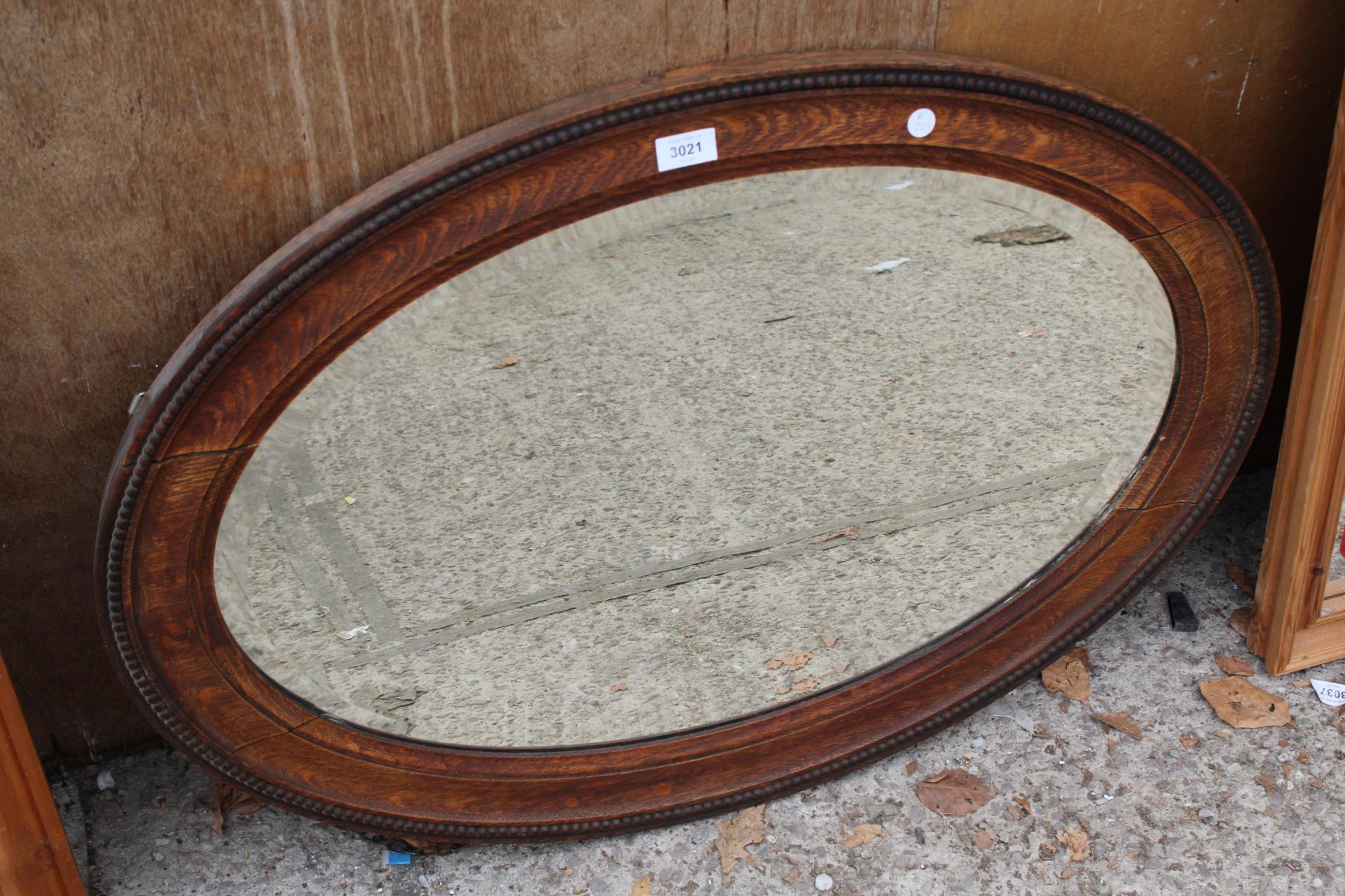 A MID 20TH CENTURY OVAL OAK BEVEL EDGED MIRROR 34" X 24"