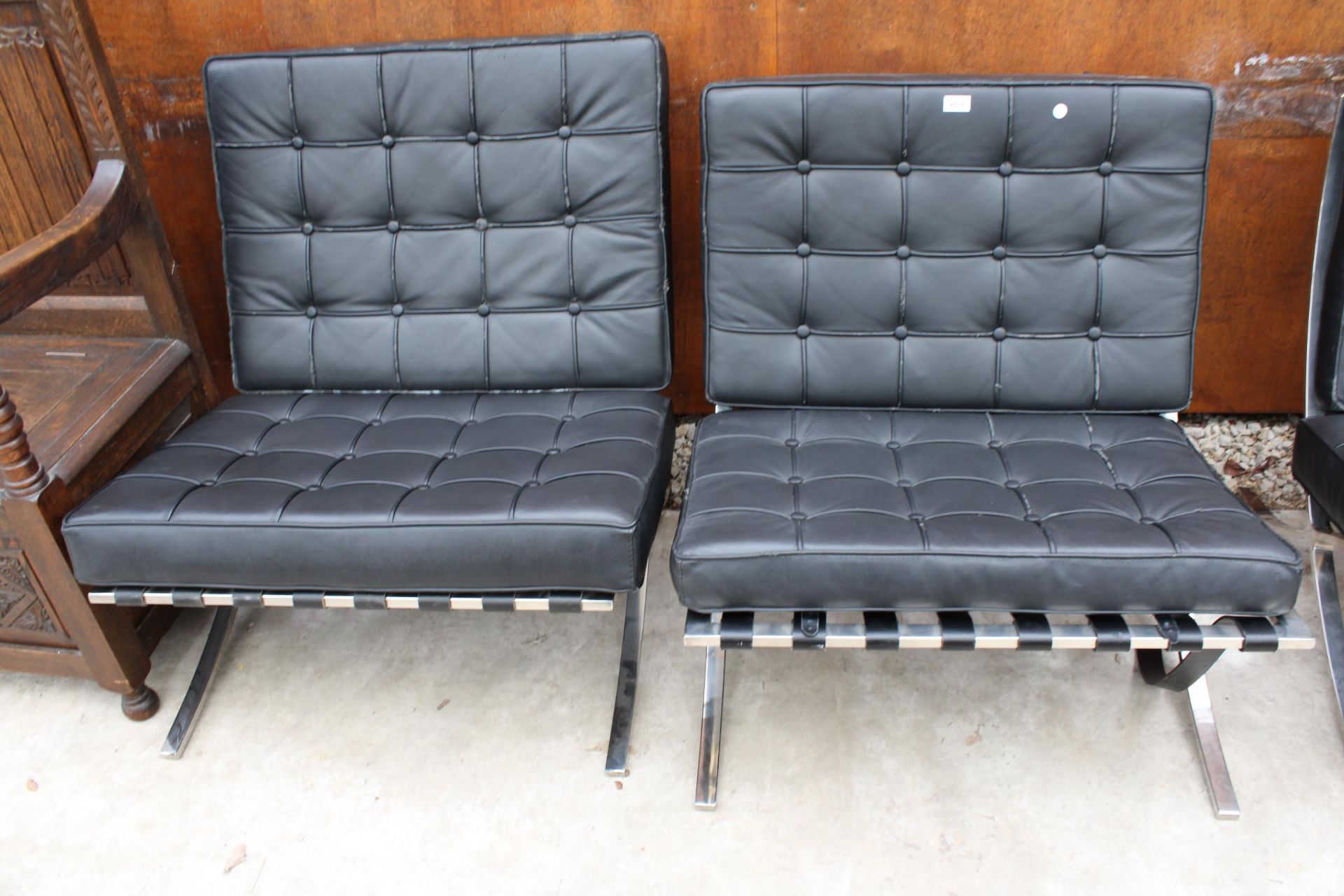A PAIR OF BLACK BARCELONA STYLE CHAIRS ON POLISHED CHROME X FRAME LEGS