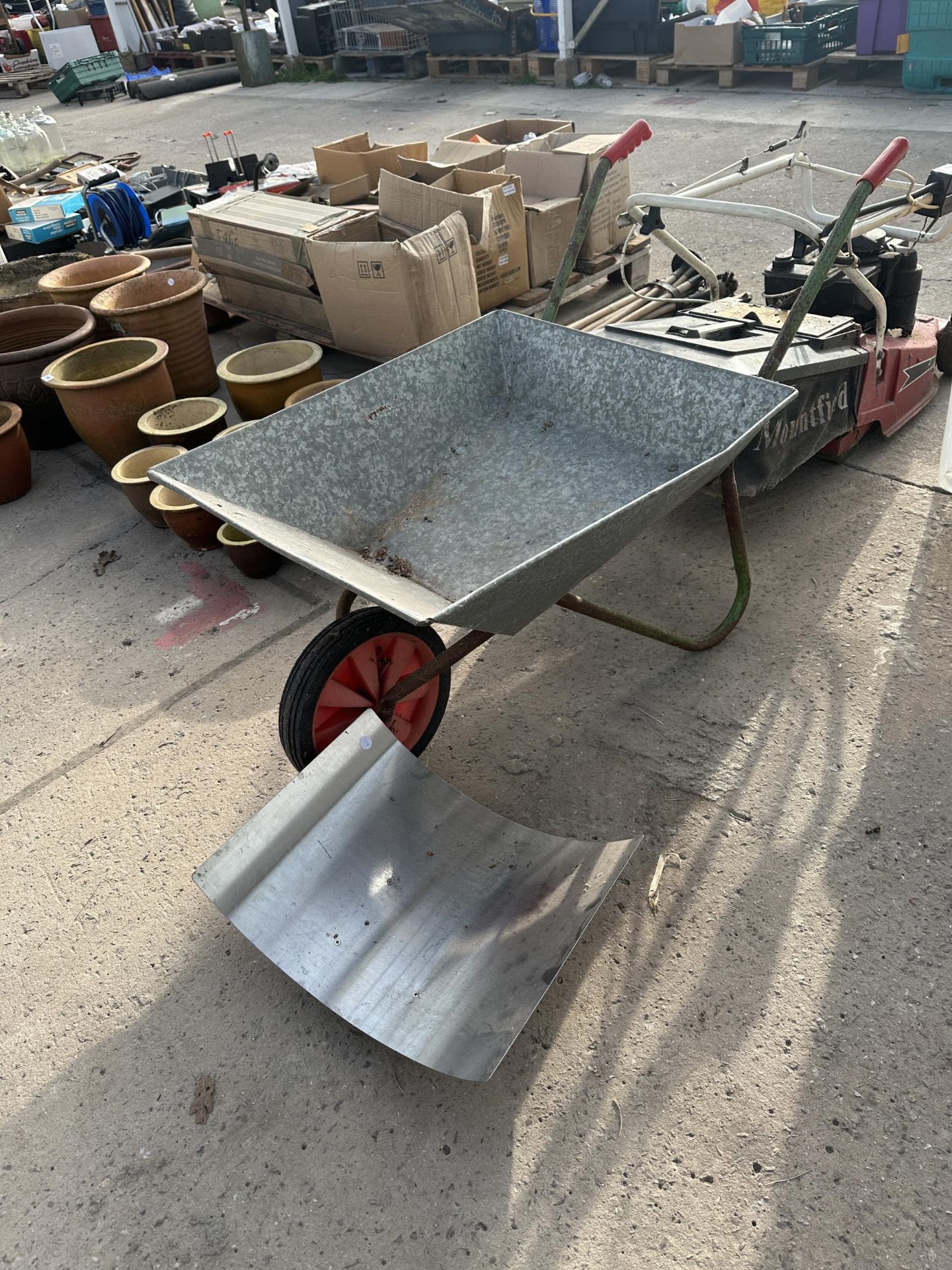 A METAL WHEEL BARROW AND A STAINLESS STEEL LOG STAND
