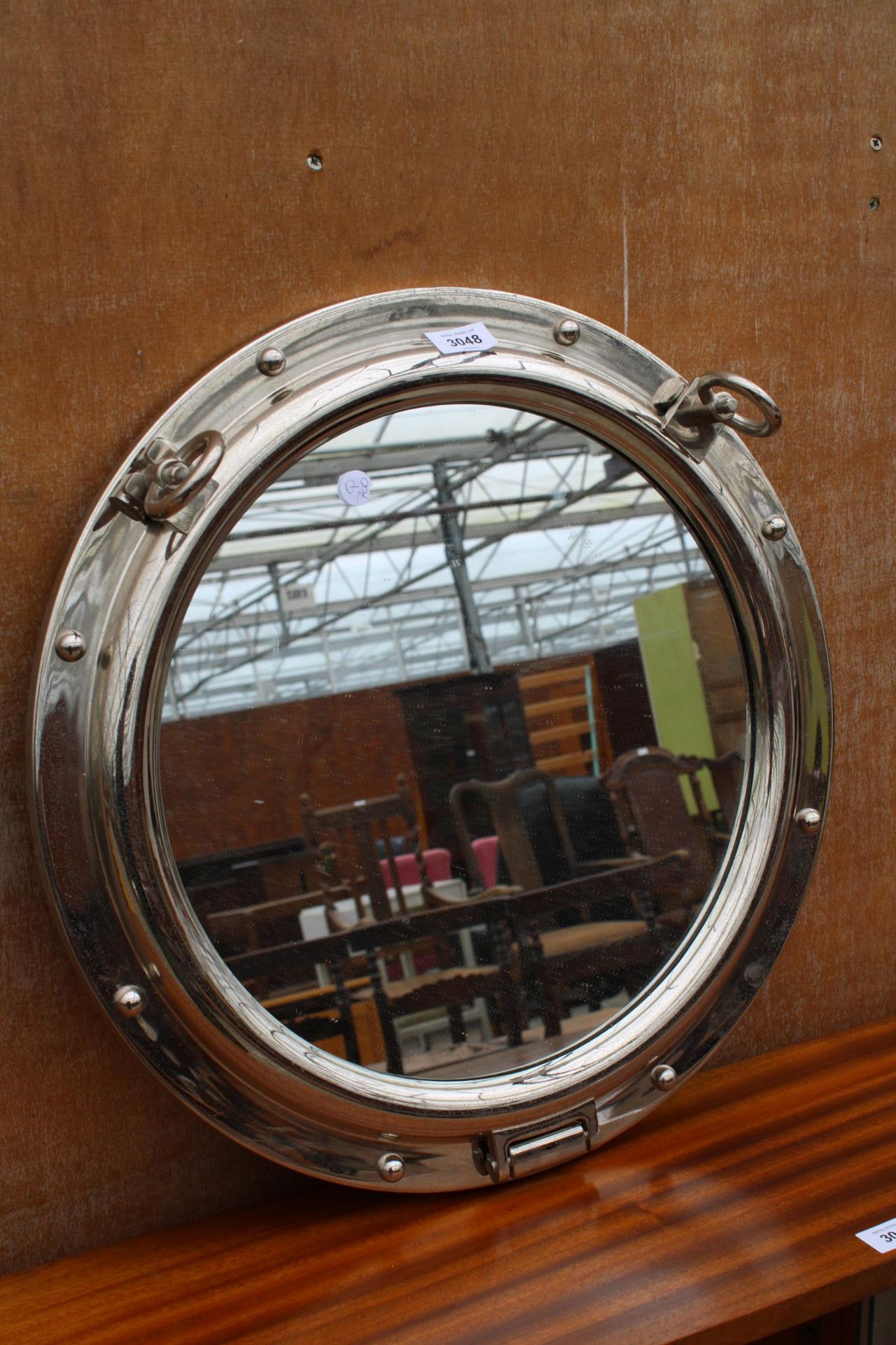 A CHROME WALL MIRROR IN THE FORM OF A PORTHOLE