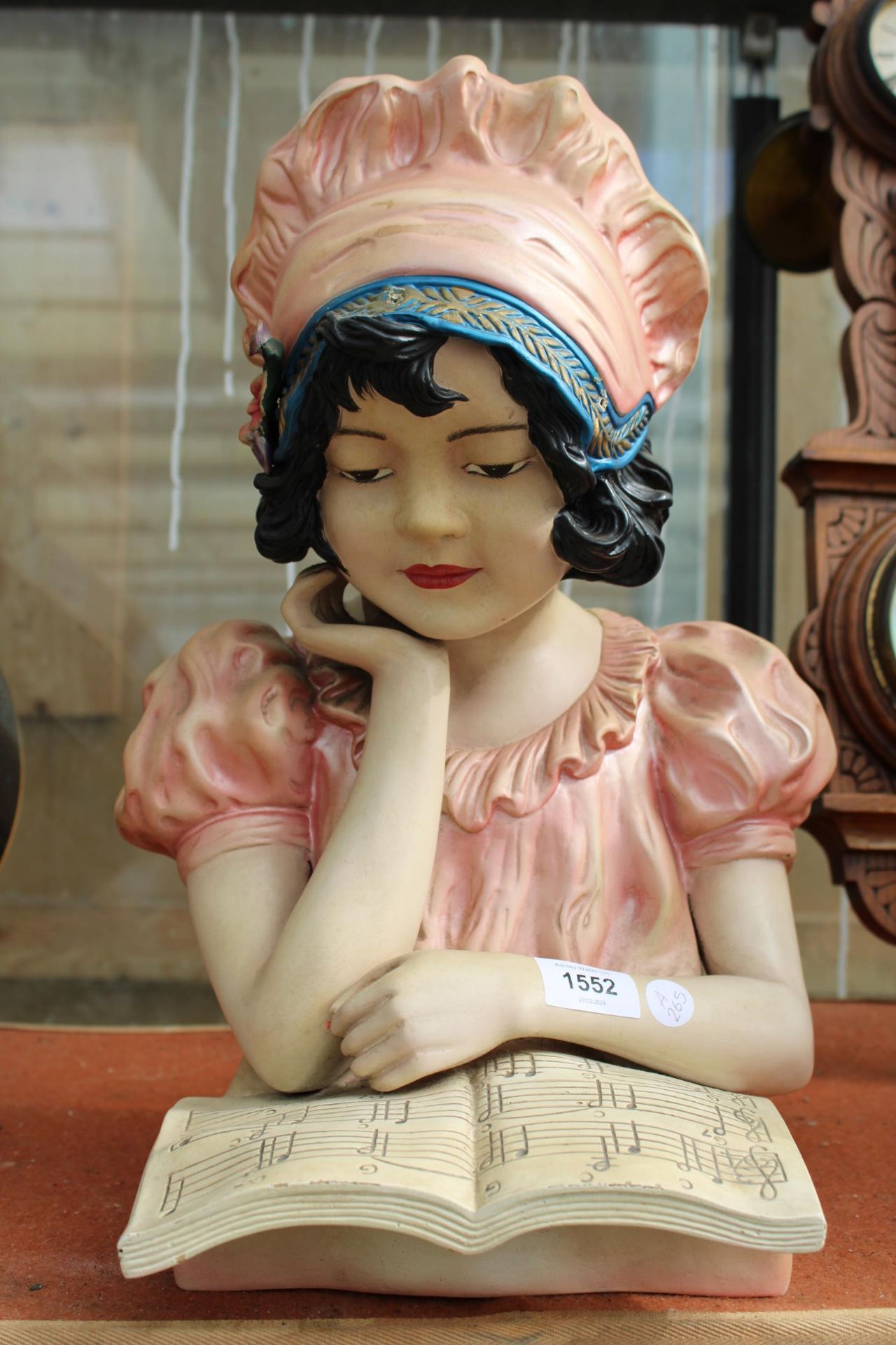 A HARD PLASTIC FIGURE OF A GIRL READING SHEET MUSIC