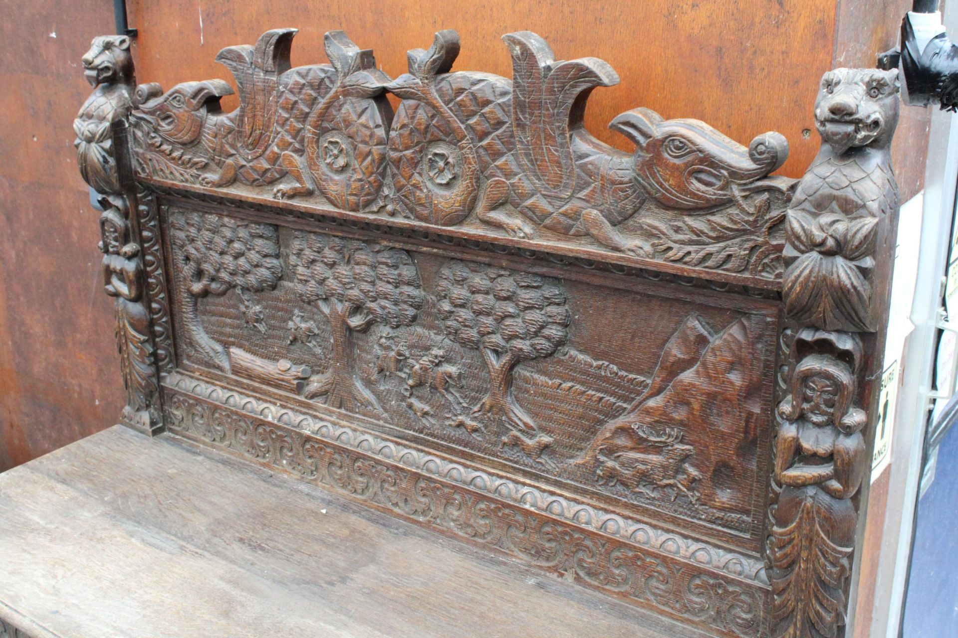 A HEAVILY CARVED GOTHIC OAK SIDEBOARD WITH DEER HUNTING SCENE AND MYTHICAL FIGURE, RAISED BACK, - Image 3 of 5