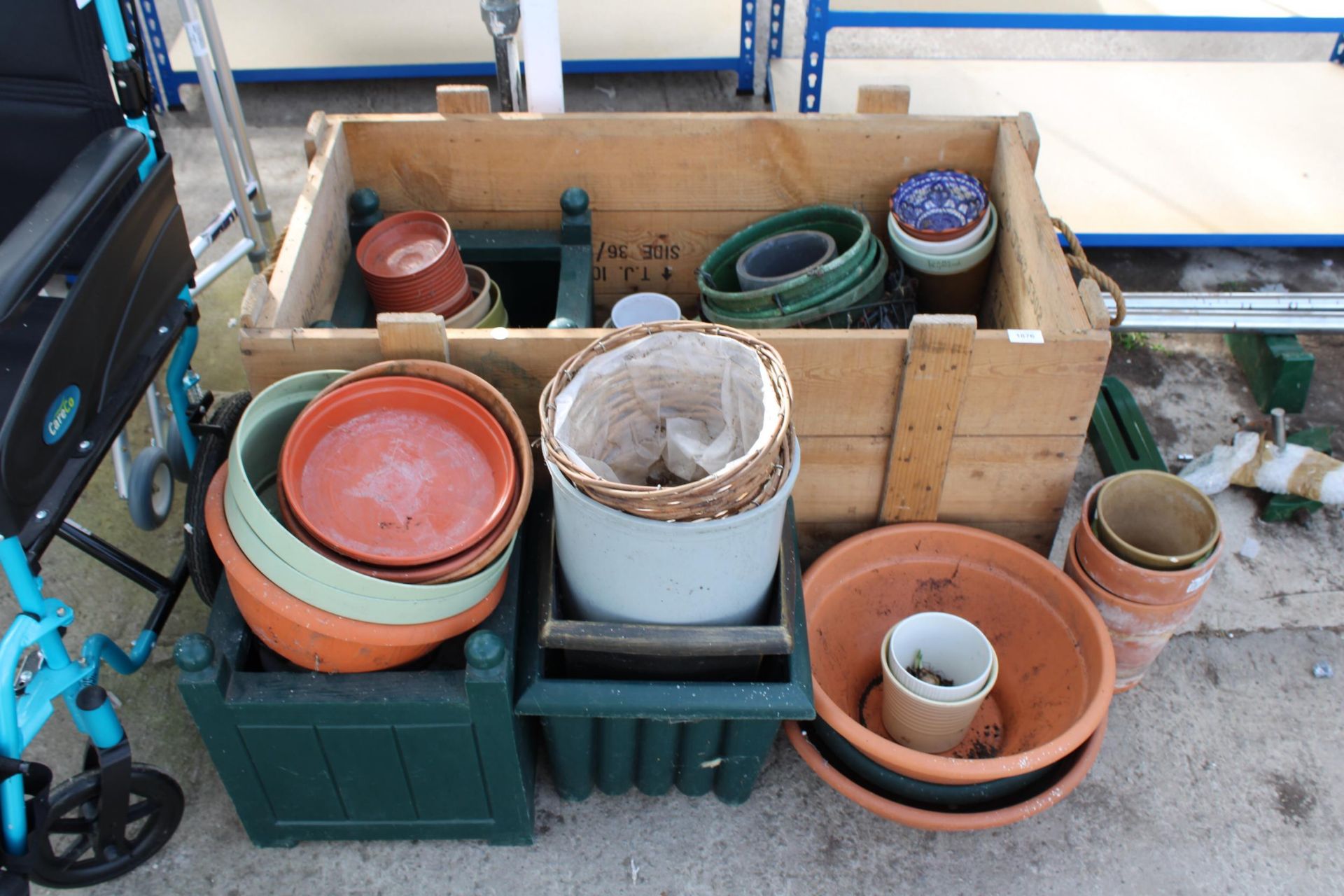 A LARGE WOODEN CRATE WITH ROPE HANDLES AND AN ASSORTMENT OF PLASTIC, WOODEN AND TERRACOTTA PLANT