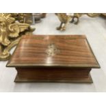 A MAHOGANY BOX IN THE SHAPE OF A BOOK WITH BRASS EDGES AND AN ANCHOR MOTIF TO THE LID