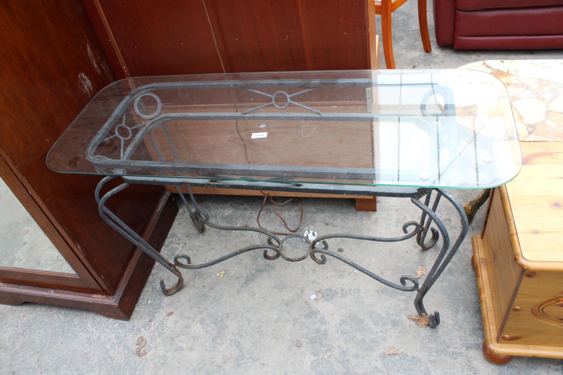 A GLASS TOP SIDE TABLE ON A METALWARE BASE 48" WIDE