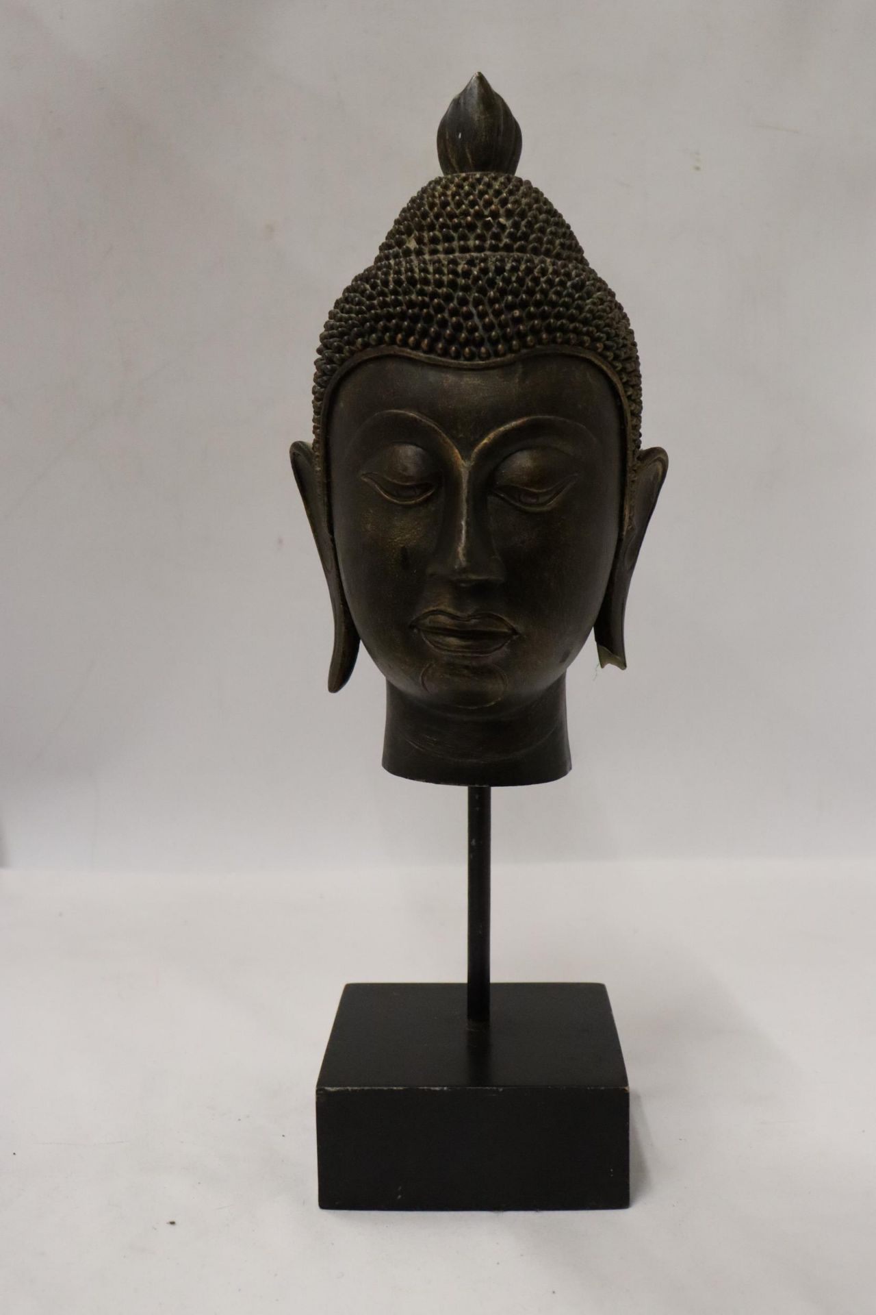 A BUDDAH'S HEAD ON A STAND, HEIGHT 36CM