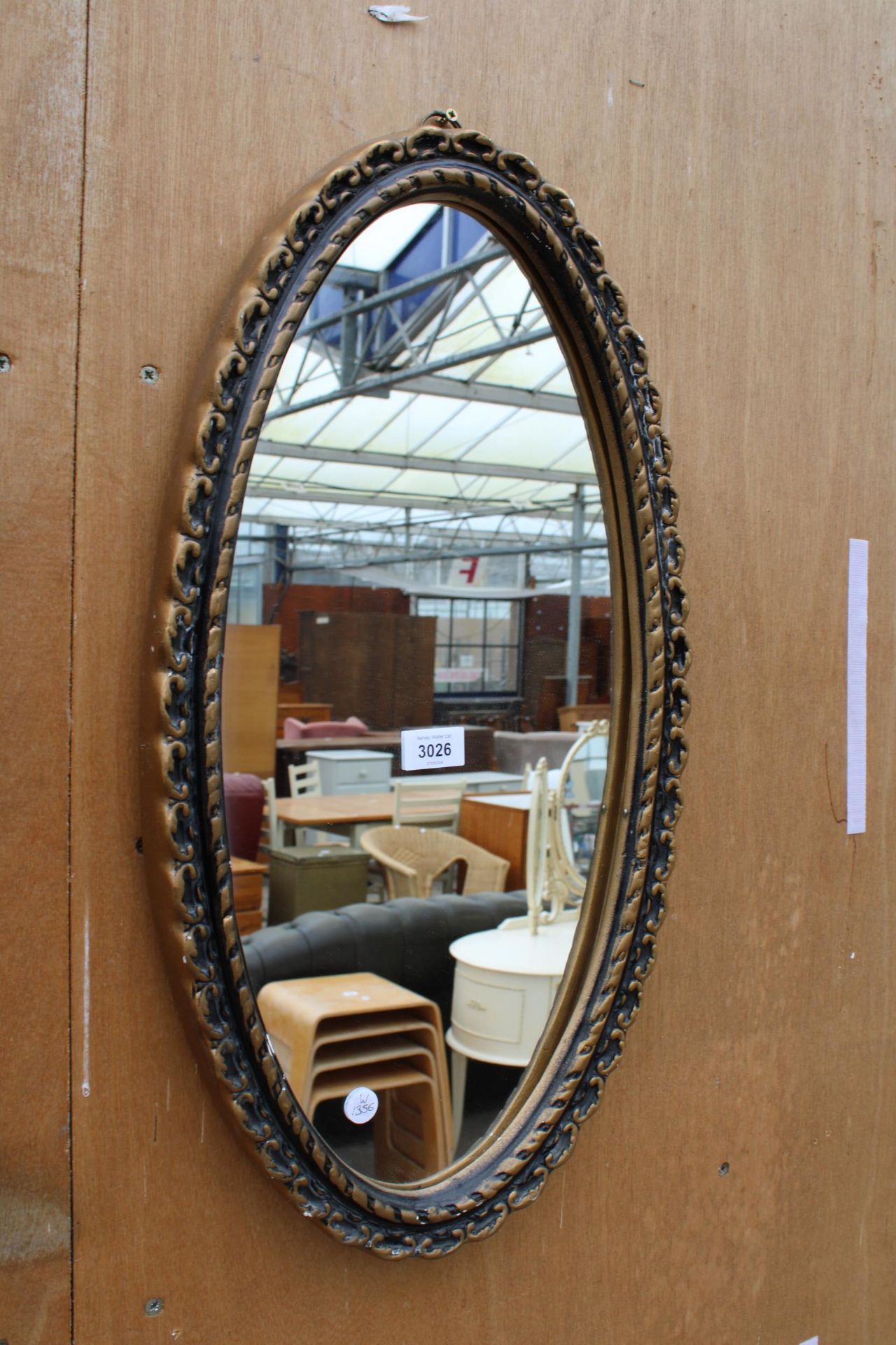 A GILT EFFECT OVAL WALL MIRROR 24" x 13"