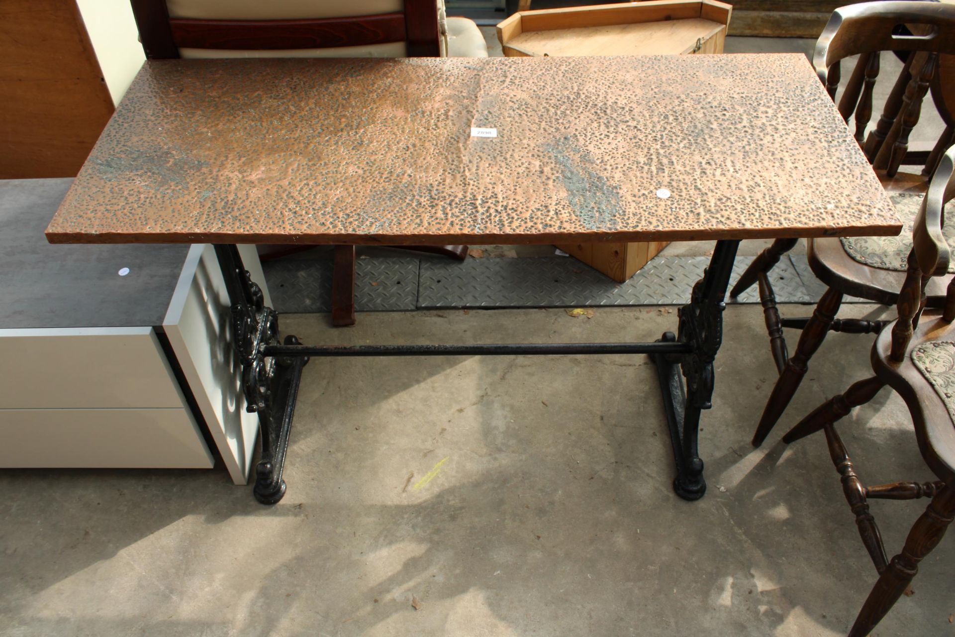 A PUB TABLE WITH AN EMBOSSED COPPER TOP 45" X 18" ON A CAST IRON BASE