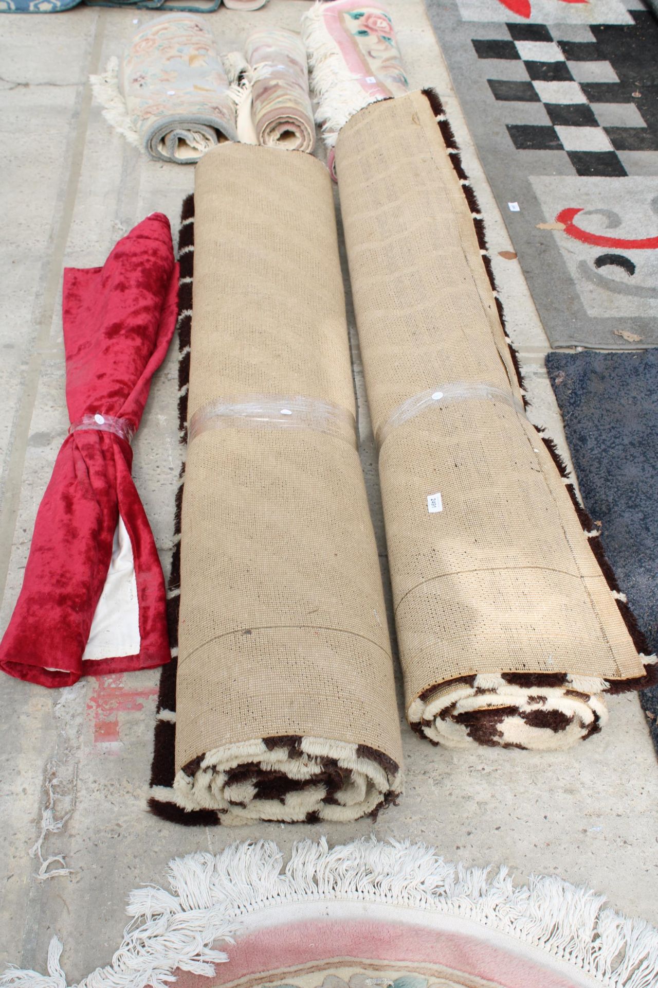 TWO LARGE BROWN PATTERNED RUGS AND A ROLL OF MATERIAL