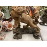 AN ORIENTAL WOODEN SCULTURE OF A BIG CAT, MARKED TO THE BASE, ON A PLINTH, HEIGHT 20CM, LENGTH 18CM