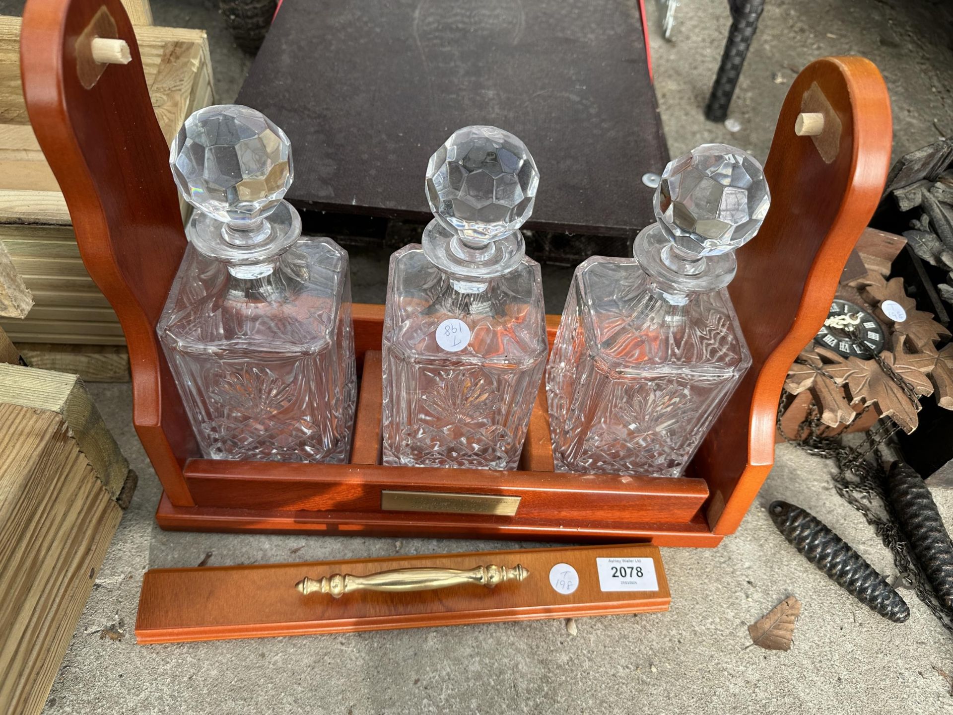 AN MDF TANTALUS AND THREE CUT GLASS DECANTERS