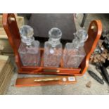 AN MDF TANTALUS AND THREE CUT GLASS DECANTERS