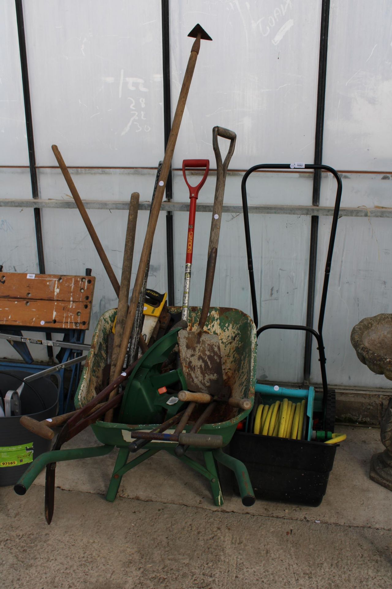 AN ASSORTMENT OF GARDEN TOOLS TO INCLUDE A HOSE PIPE, A PUSH MOWER AND A WHEEL BARROW ETC