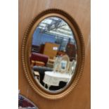 A GOLD PAINTED OVAL BEVEL EDGE MIRROR - 34" X 24"