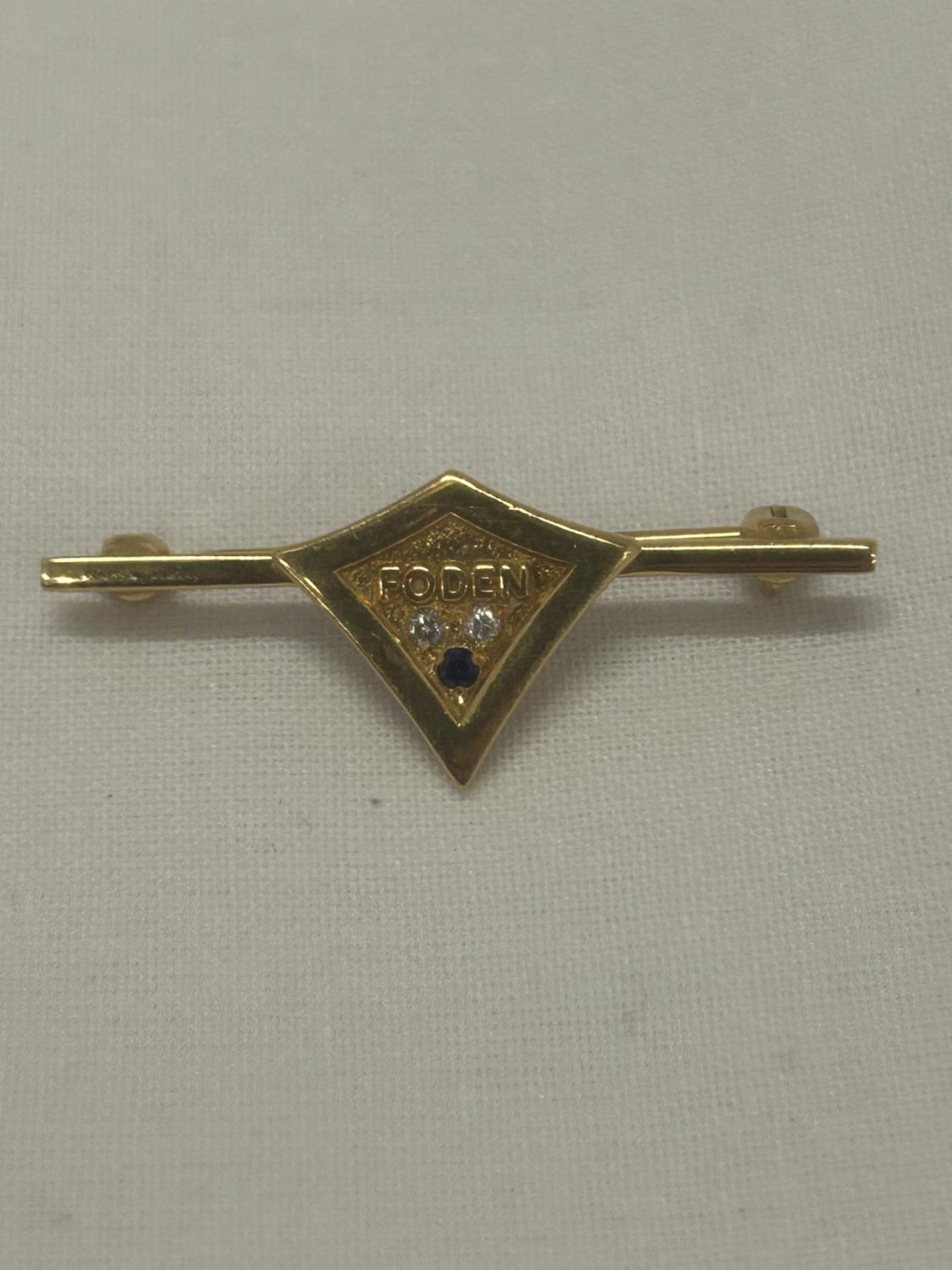 A HALLMARKED 9CT GOLD DIAMOND AND SAPPHIRE 'FODEN' BADGE WEIGHT 3.37G