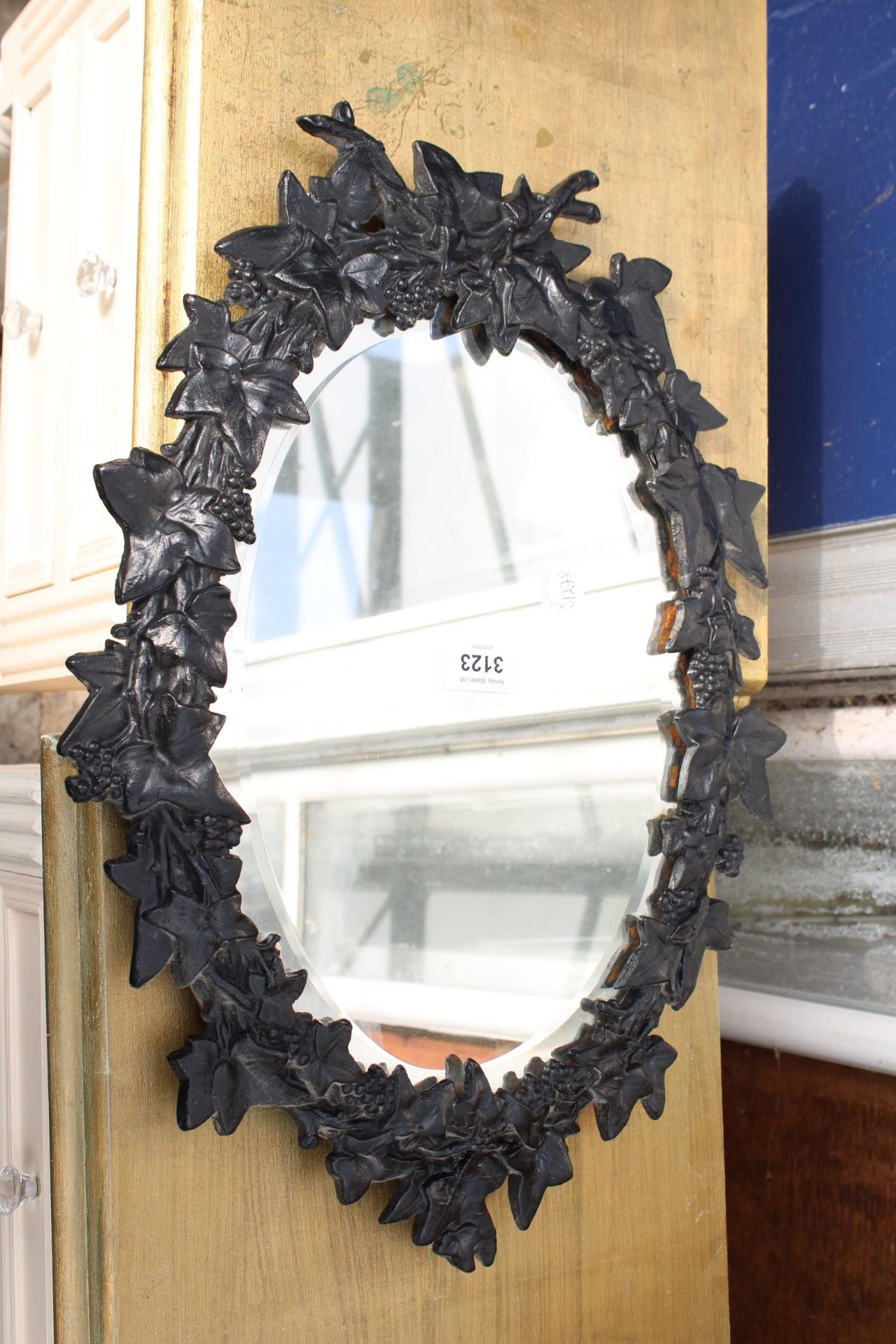 A VICTORIAN STYLE CAST IRON WALL MIRROR WITH VINE LEAF DECORATION, 19" X 14"