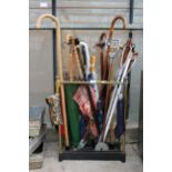 A VINTAGE CAST IRON AND BRASS COATED STICK STAND WITH A LARGE ASSORTMENT OF WALKING STICKS AND