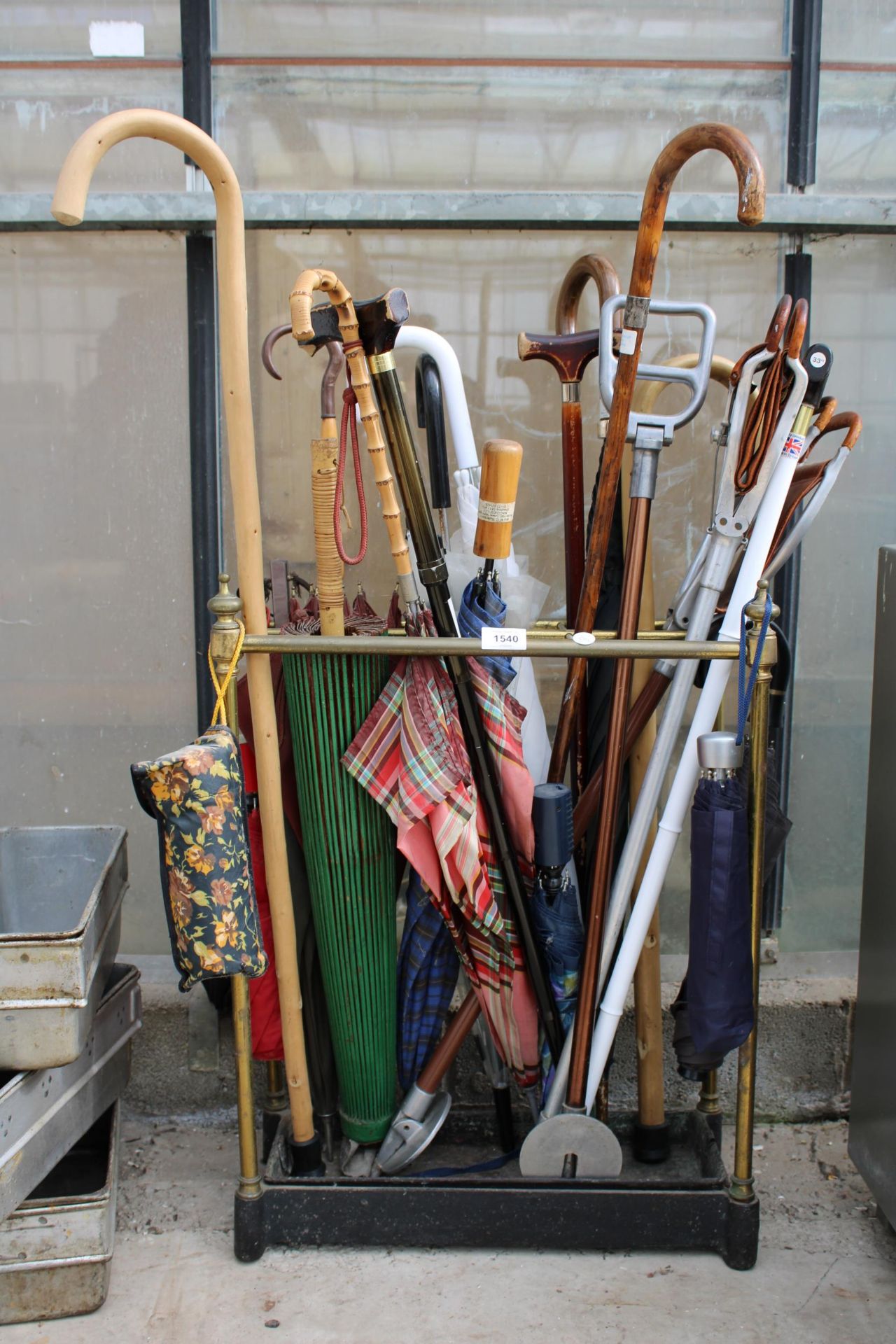 A VINTAGE CAST IRON AND BRASS COATED STICK STAND WITH A LARGE ASSORTMENT OF WALKING STICKS AND