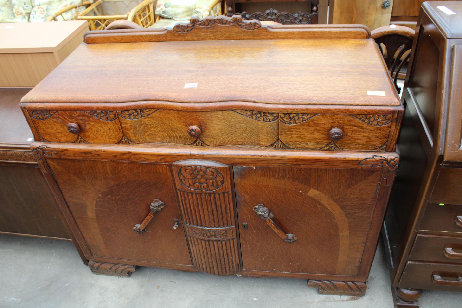 AN EARLY TWENTIETH CENTURY OAK SIDEBOARD ENCLOSING THREE DRAWERS AND TWO CUPBOARDS, 48" WIDE