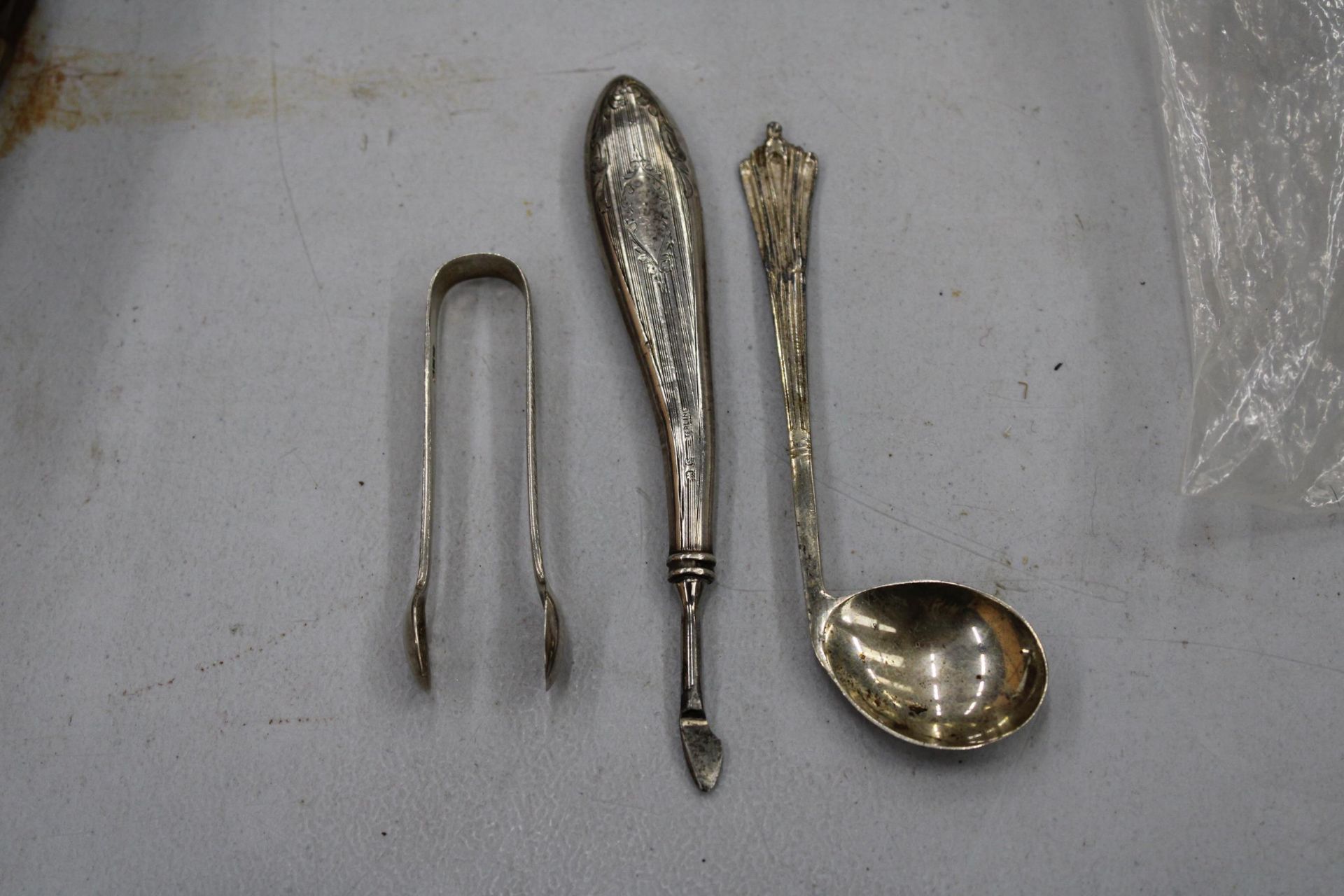 THREE MARKED SILVER ITEMS TO INCLUDE A GOLF CLUB SHAPED SPOON, SUGAR TONGS AND A MANICURE TOOL