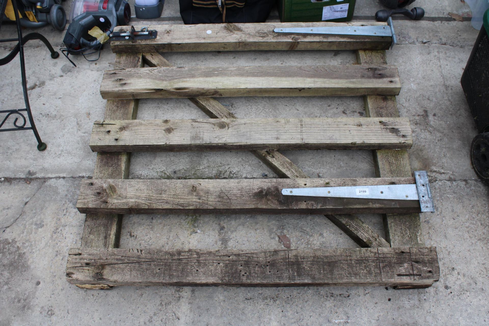 A WOODEN GATE WITH HINGES AND A QUALCAST ELECTRIC LAWN MOWER