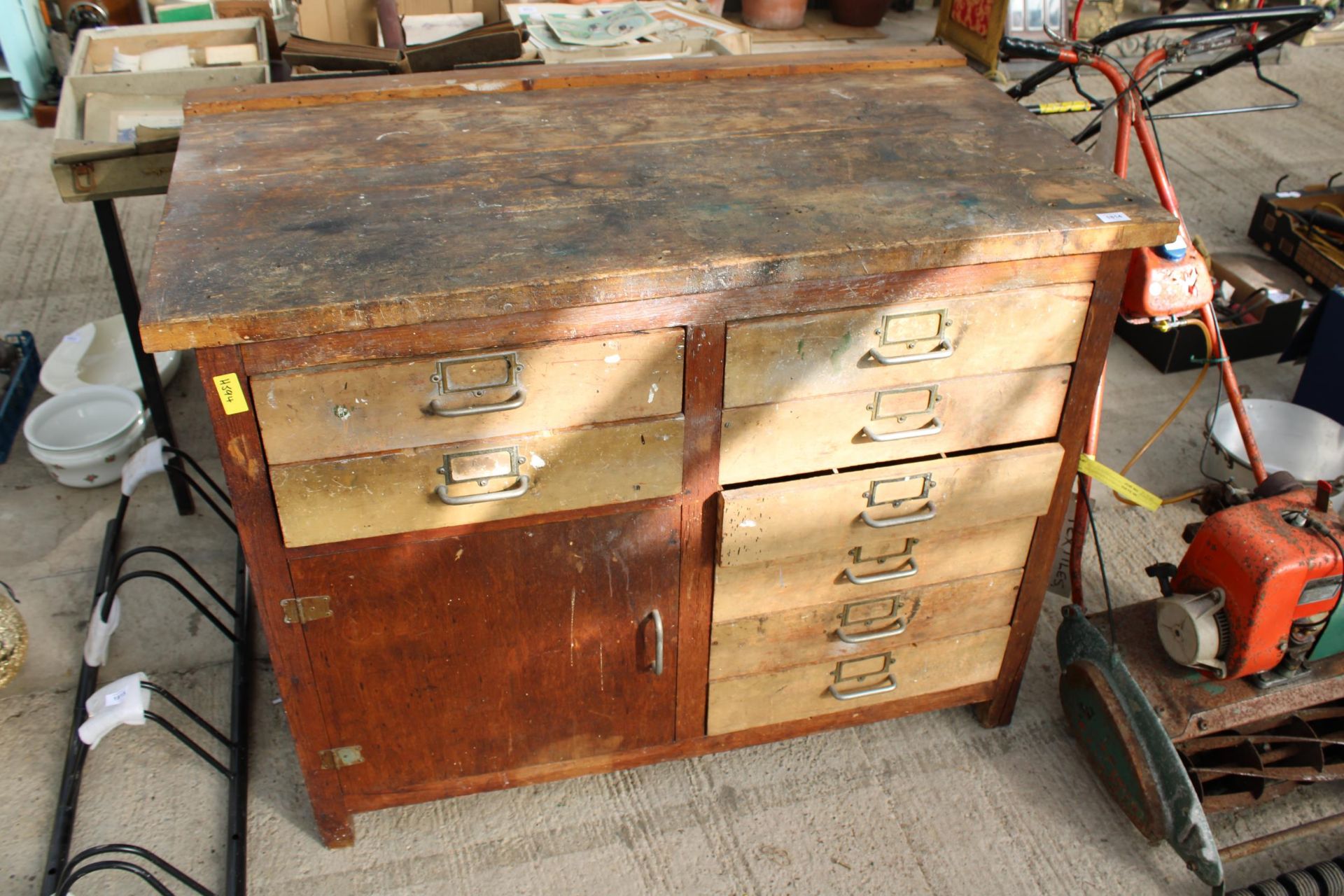 A VINTAGE WOODEN WORK BENCH WITH 8 DRAWERS AND A LOWER CUPBOARD (L:119CM)