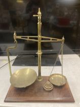 A SET OF BRASS BALANCE SCALES ON A WOODEN BASE WITH WEIGHTS W & T AVERY