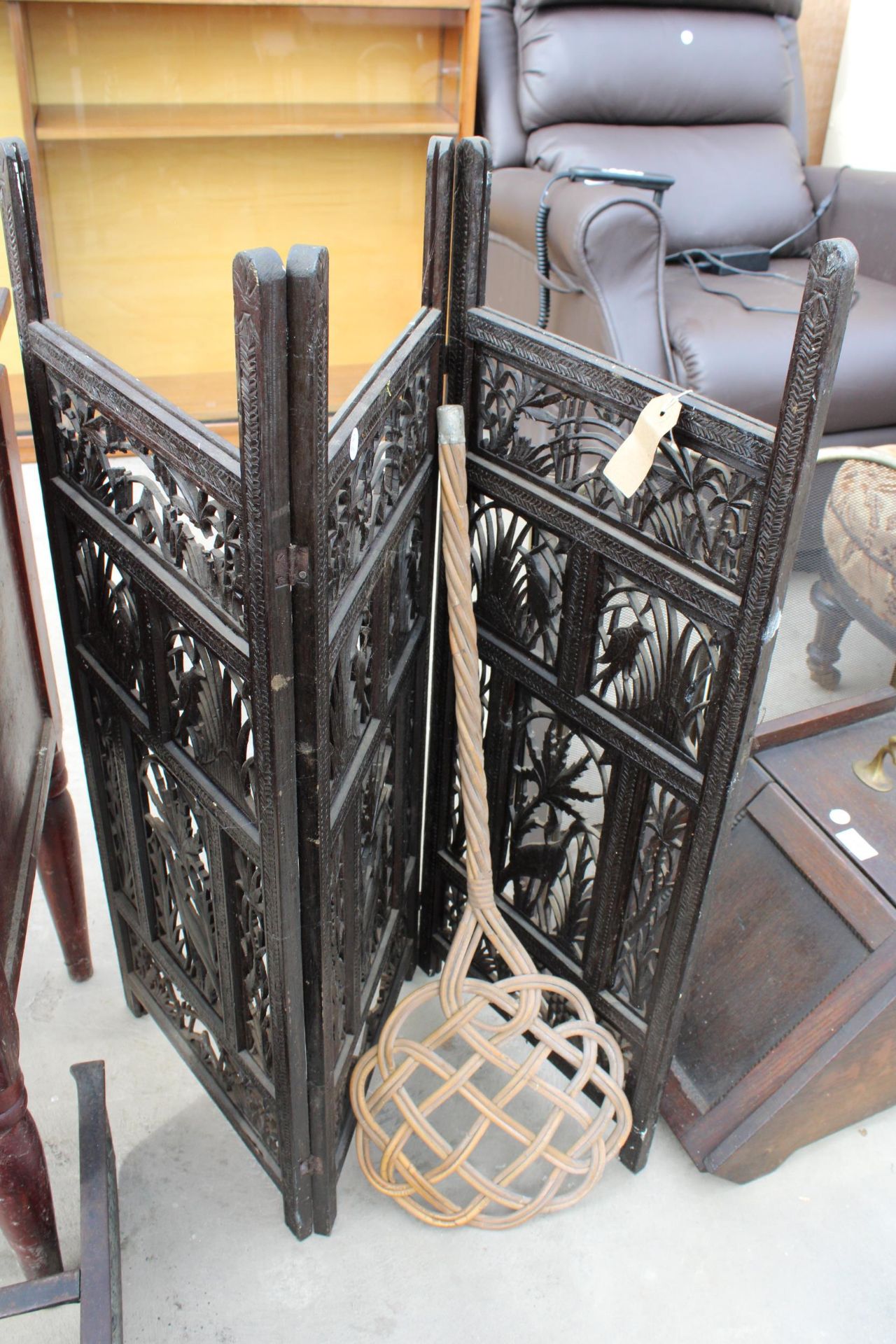 AN EBONISED THREE DIVISION PIRECED SCREEN AND CARPET BEATER