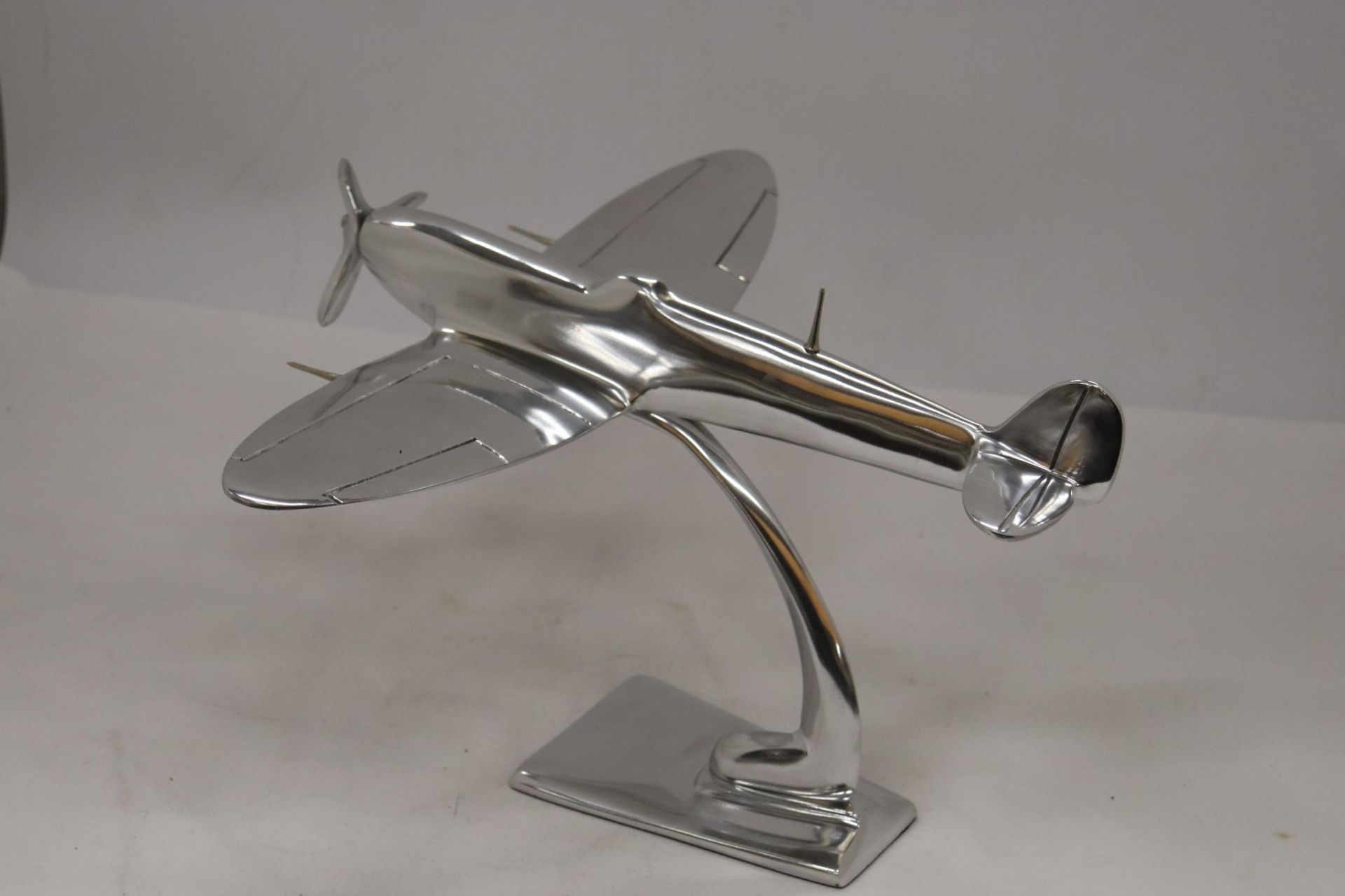 A LARGE CHROME SPITFIRE ON A STAND