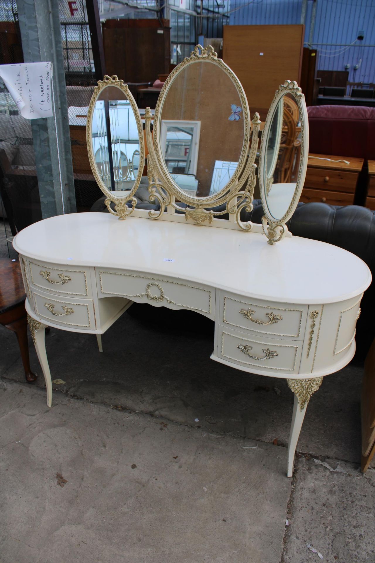 A CREAM AND GILT KIDNEY SHAPED DRESSING TABLE WITH TRIPLE MIRROR 52" WIDE
