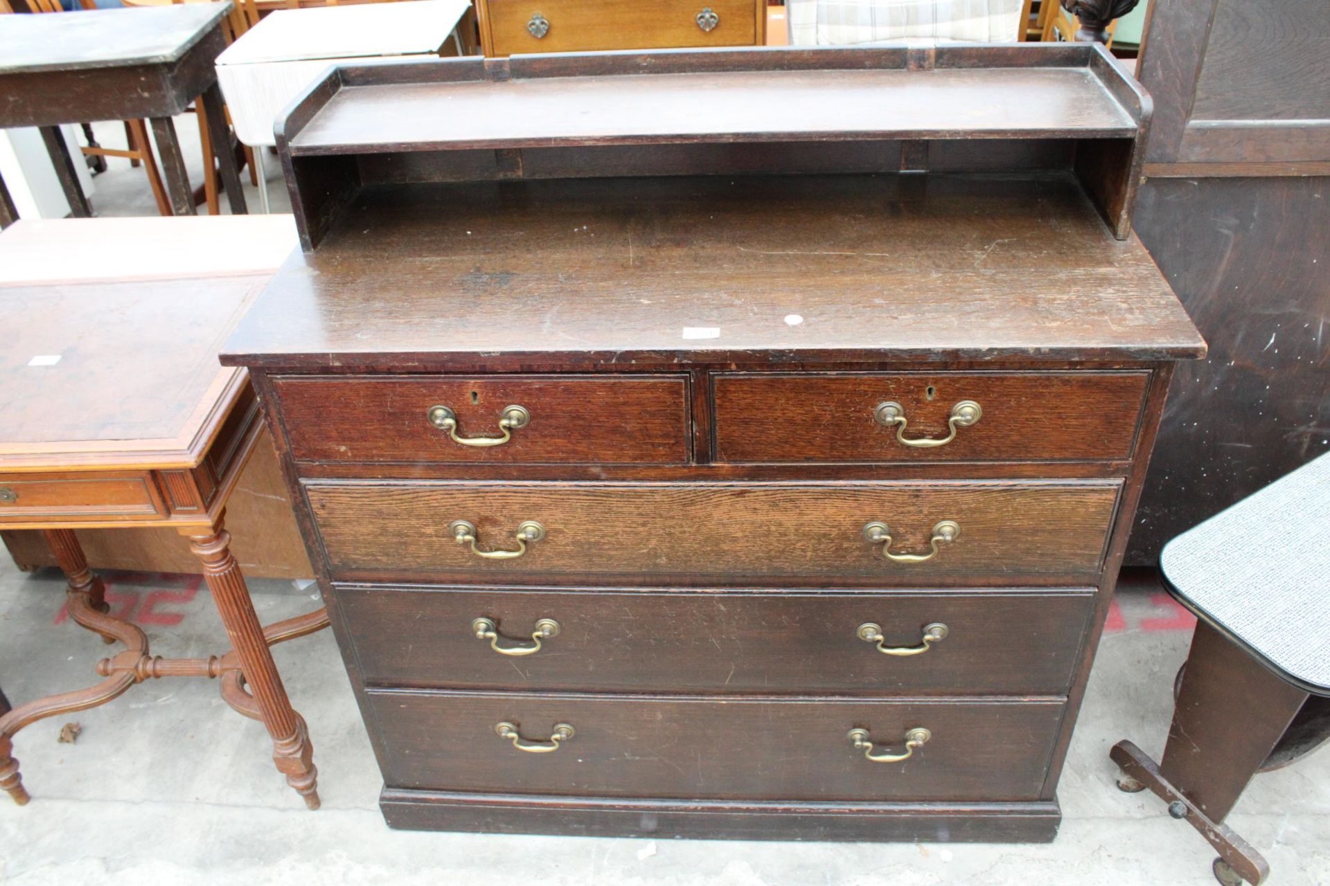 AN EARLY 20TH CENTURY OAK CHEST OF TWO SHORT AND THREE LONG GRADUATED DRAWERS WITH GALLERY SHELF