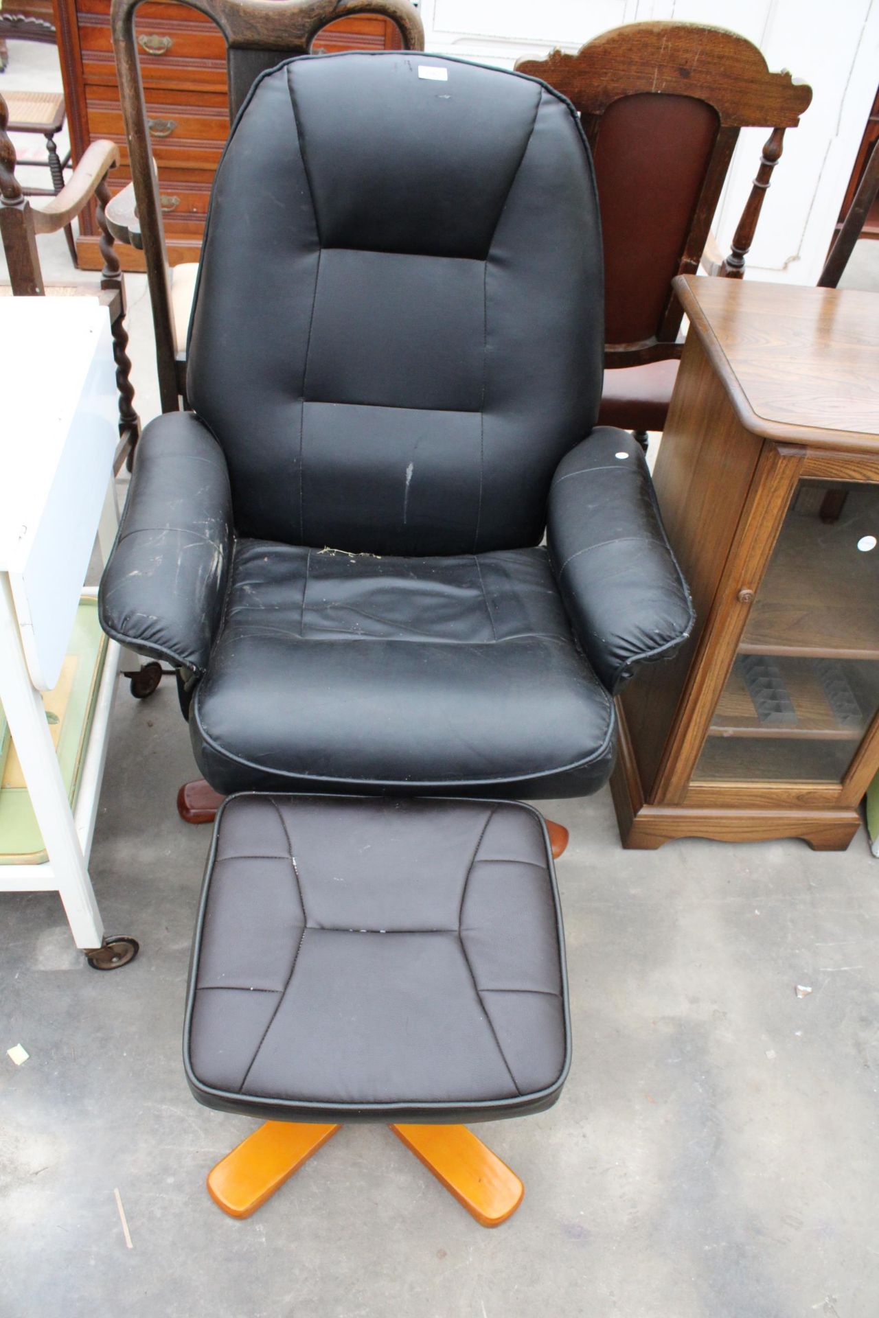 A FAUX BLACK LEATHER SWIVEL RECLINING CHAIR AND STOOL