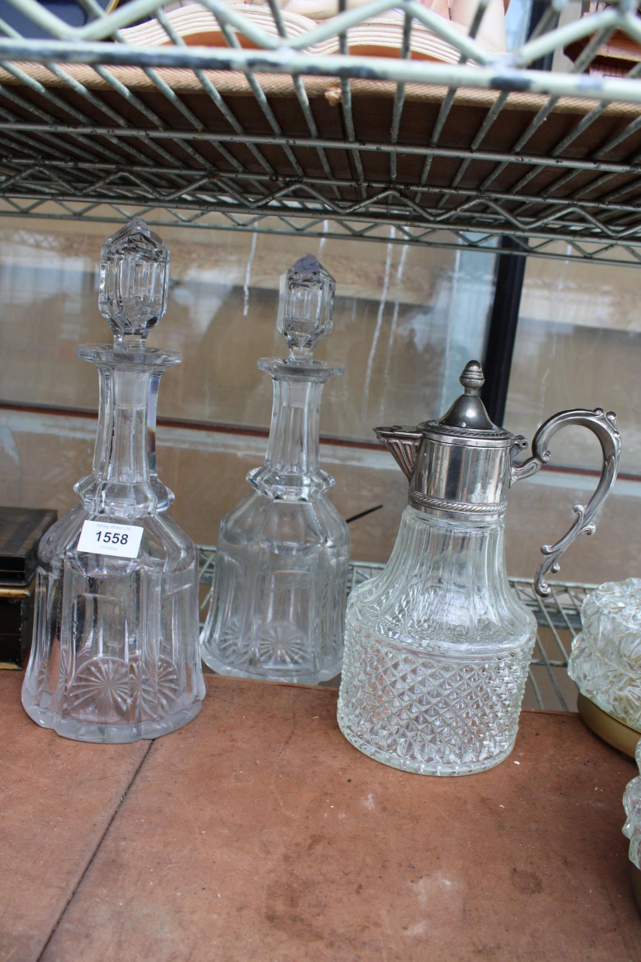 TWO GLASS DECANTORS AND A CLARET JUG WITH SILVER PLATED TOP