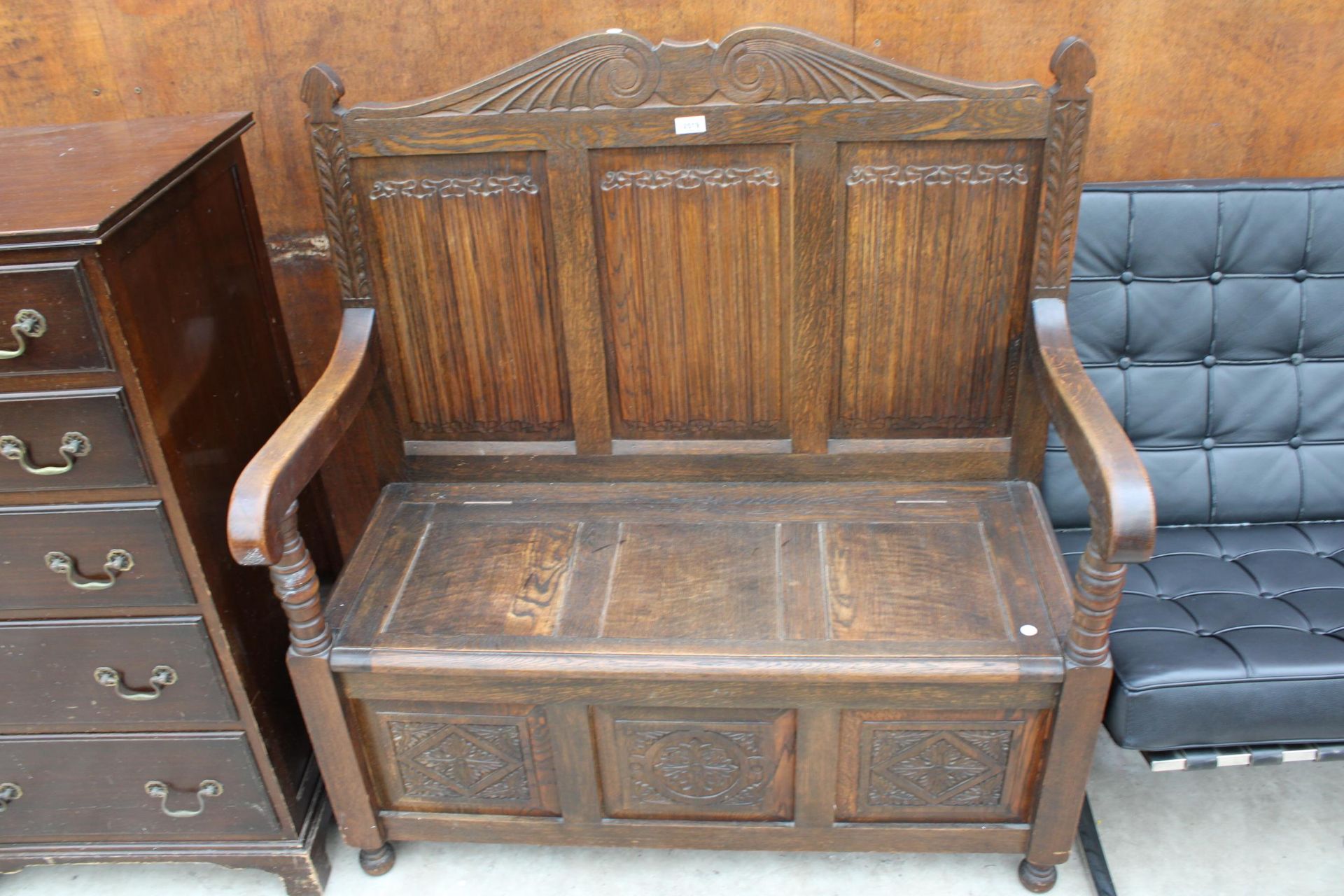 AN OAK JACOBEAN STYLE SETTLE WITH LINENFOLD BACK, CARVED PANEL FRONT AND LIFT-UP SEAT, 42" WIDE