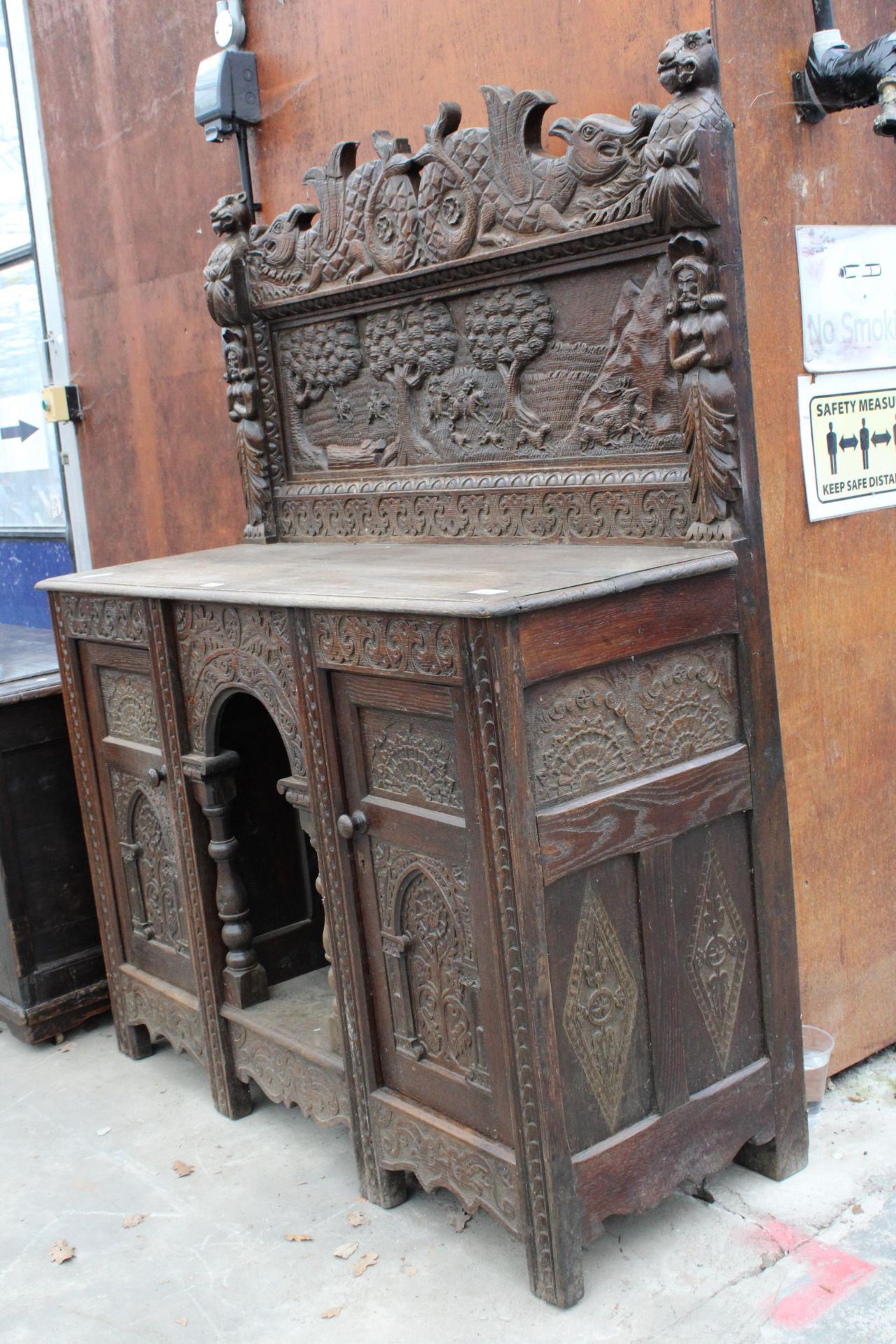 A HEAVILY CARVED GOTHIC OAK SIDEBOARD WITH DEER HUNTING SCENE AND MYTHICAL FIGURE, RAISED BACK, - Image 2 of 5