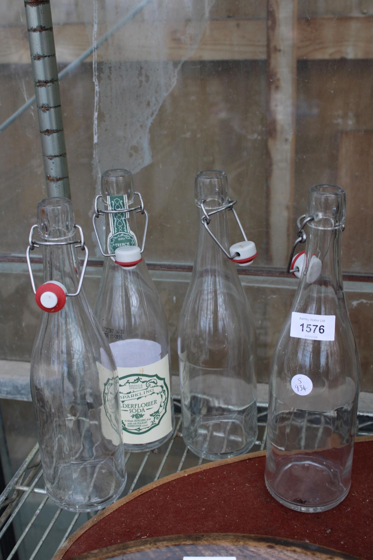 A SET OF FOUR GLASS BOTTLES WITH FLIP TOP STOPPERS