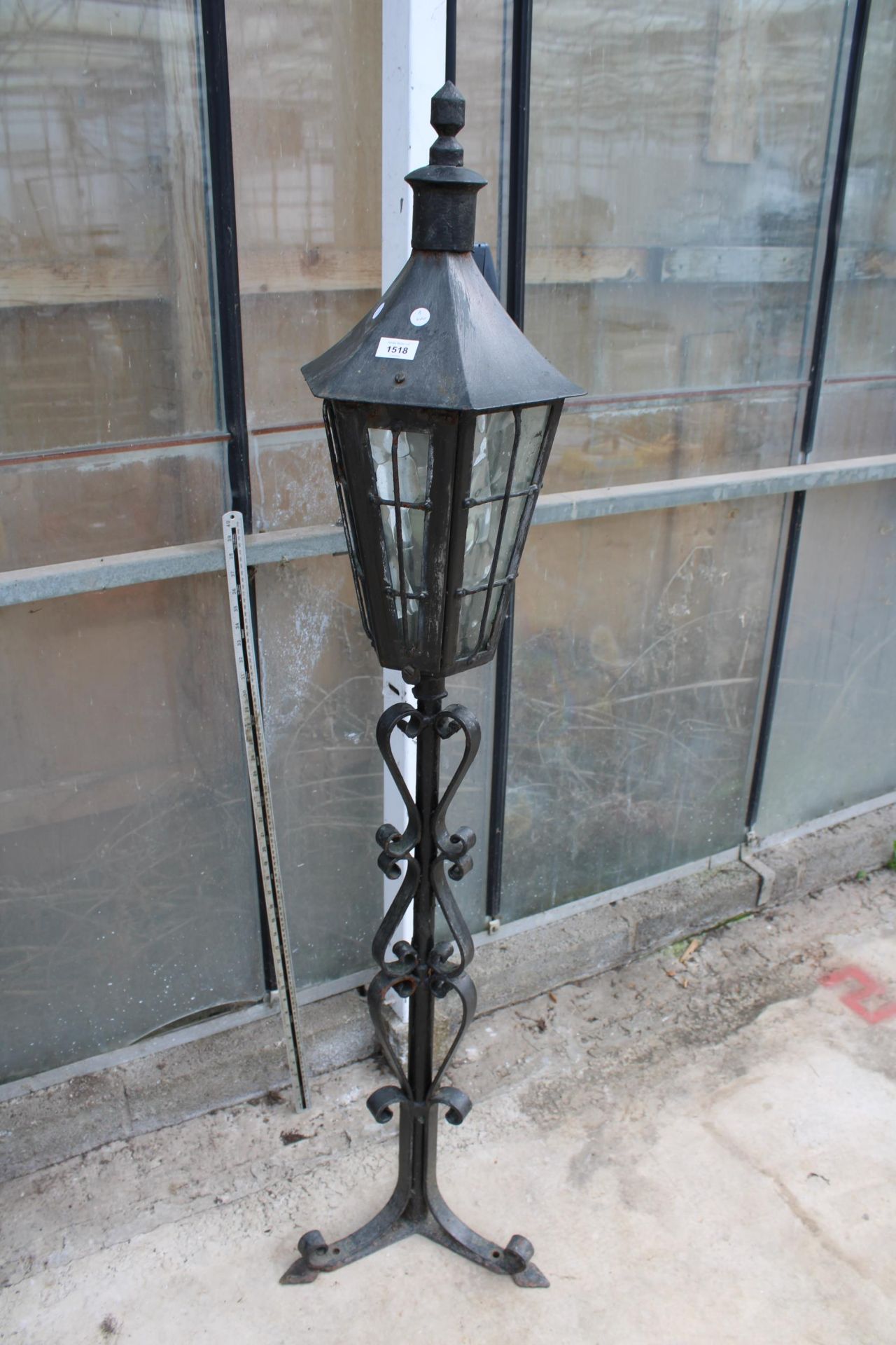 A DECORATIVE METAL LAMP POST WITH TRIPOD BASE