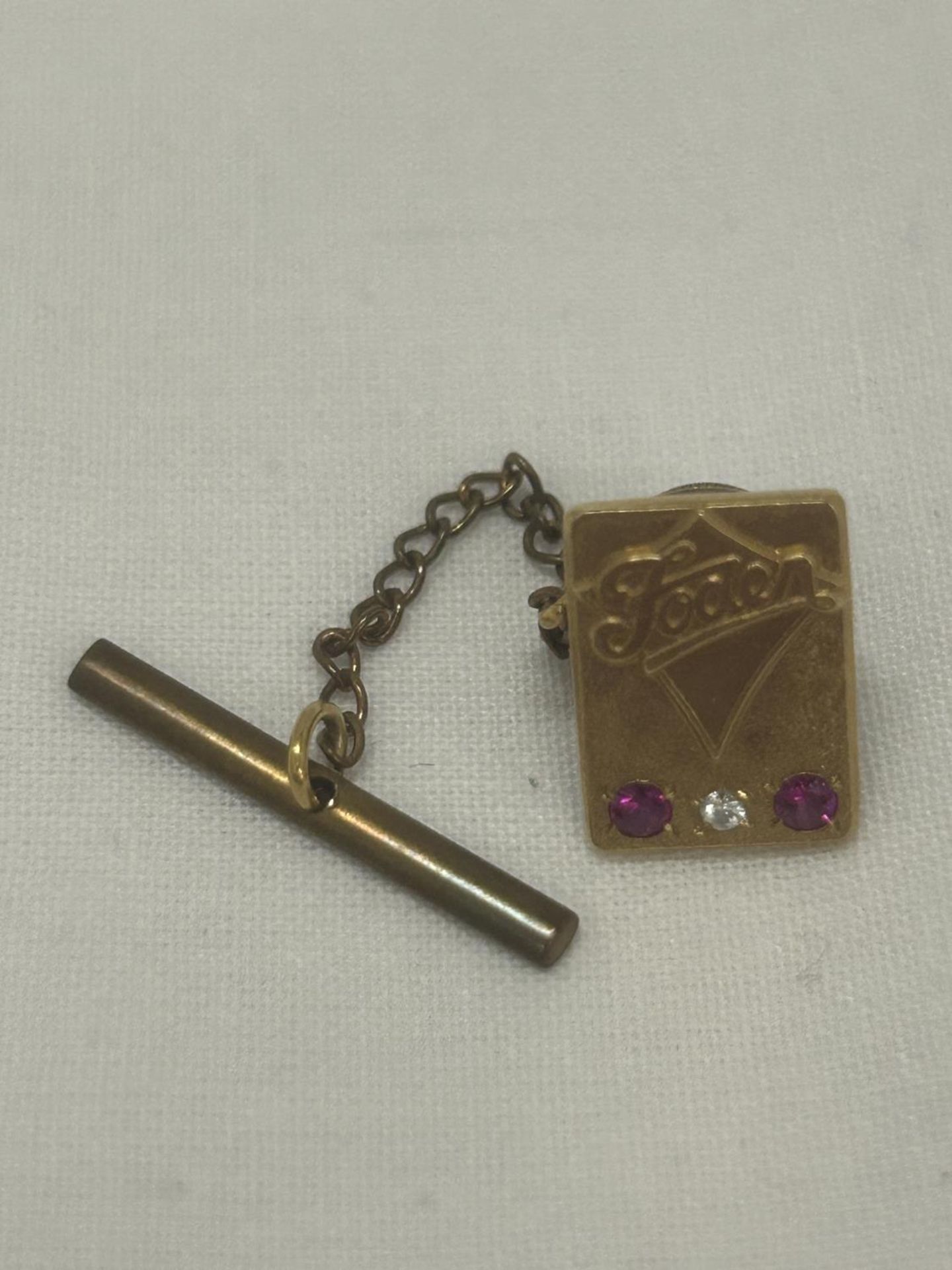 A HALLMARKED 9CT GOLD DIAMOND AND RUBY 'FODEN' PIN BADGE GROSS WEIGHT 4.84G