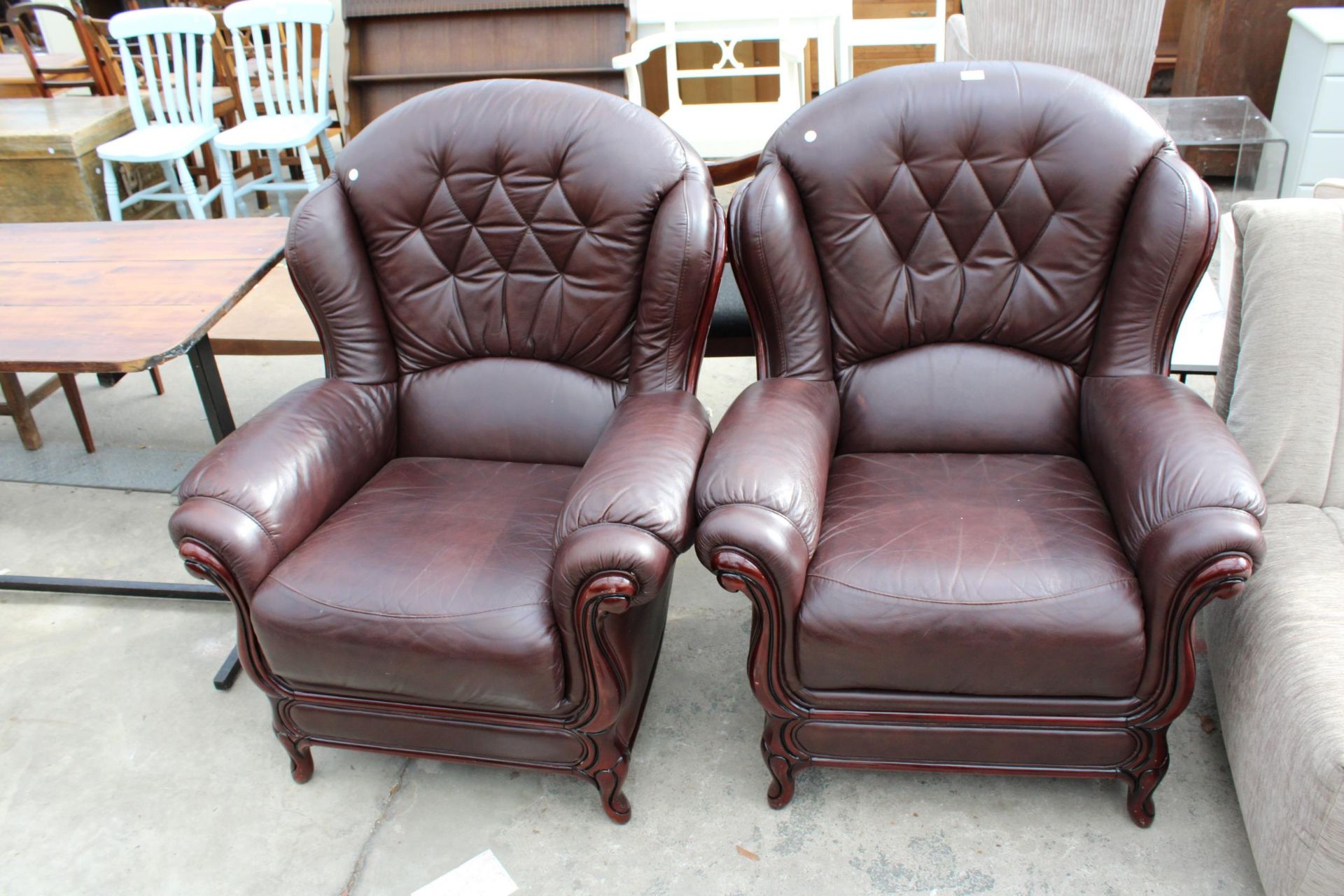 A PAIR OF RED LEATHER EASY CHAIRS WITH PARTIAL WING BACKS