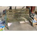 A WOODEN SLATTED GARDEN BENCH WITH DECORATIVE CAST BENCH ENDS
