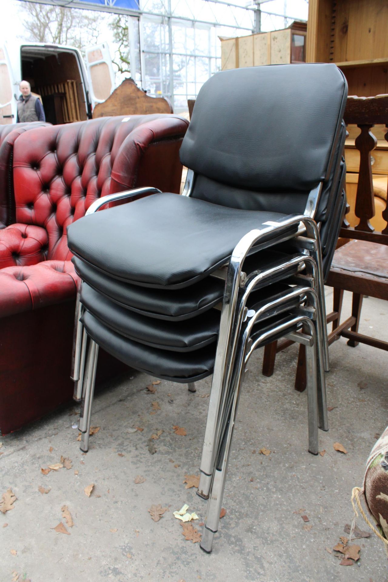 A SET OF FOUR BLACK FAUX LEATHER STACKING CHAIRS ON POLISHED CHROME FRAME