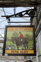 A DOUBLE SIDED WOODEN 'THE HUNTSMAN' PUB SIGN WITH CAST IRON WALL MOUNTING BRACKET