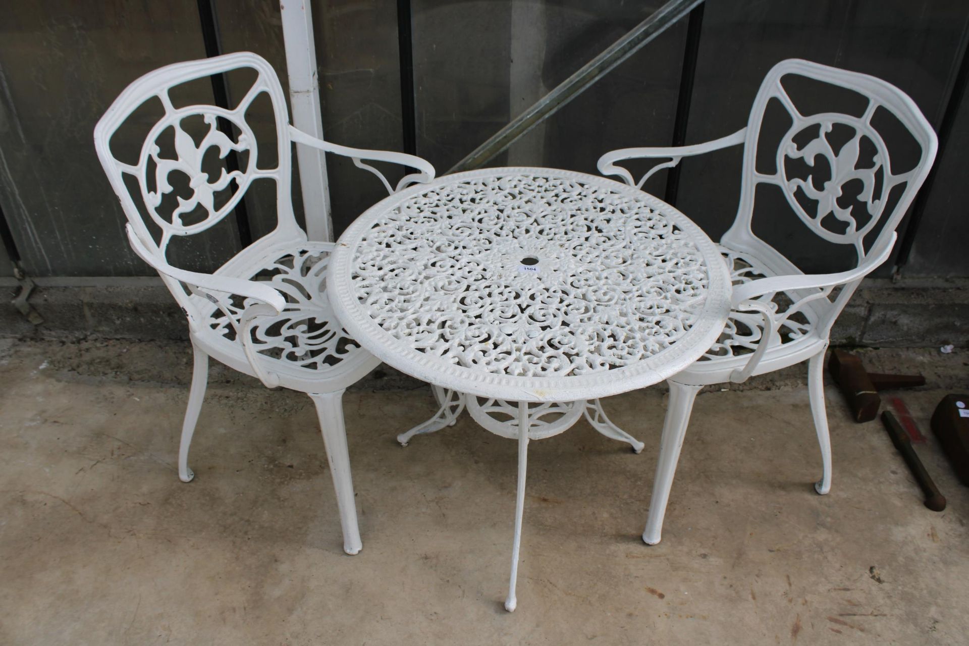 A VINTAGE WHITE CAST ALLOY BISTRO SET COMPRISING OF A ROUND TABLE AND TWO CARVER CHAIRS