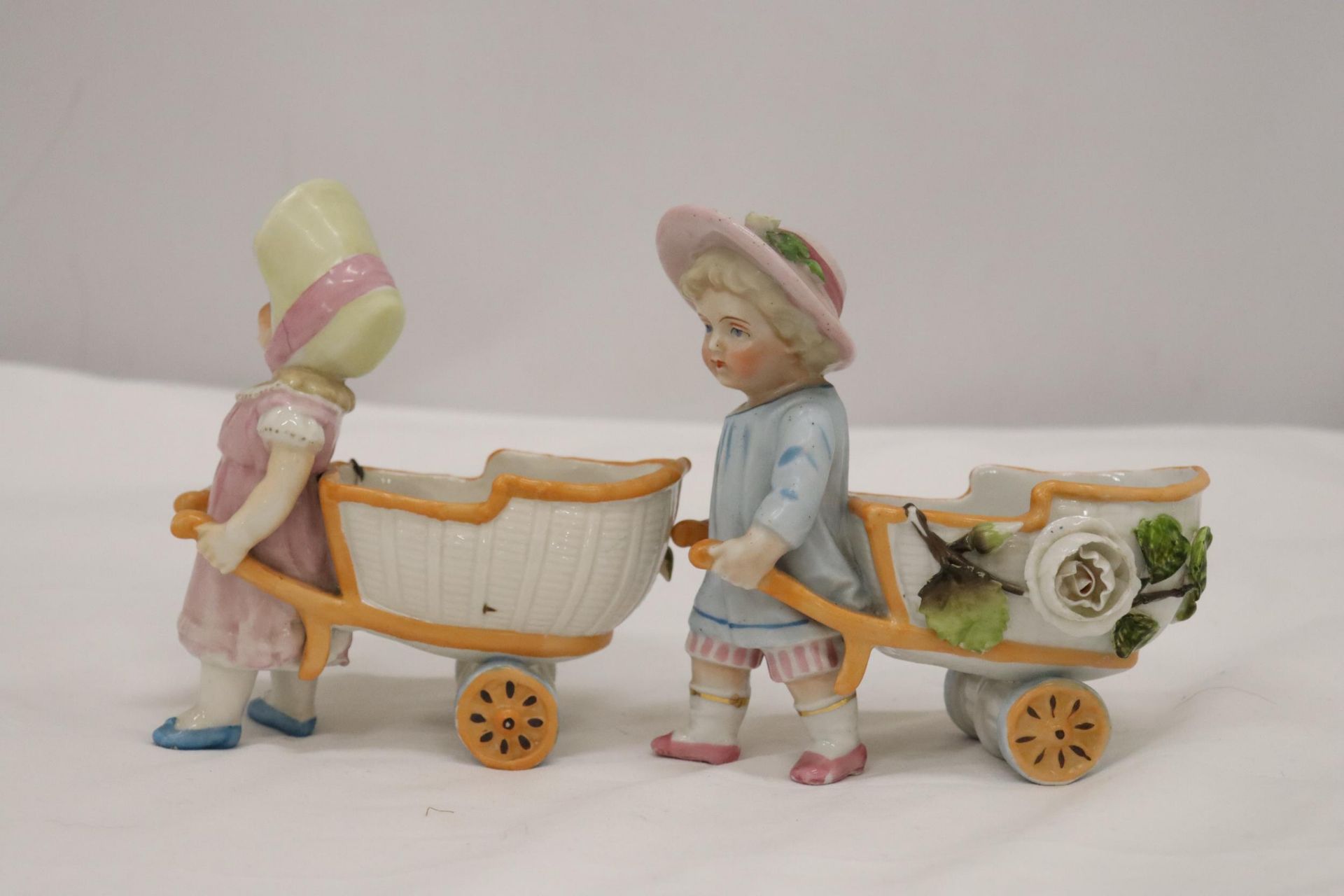 TWO VINTAGE GERMAN FAIRINGS TO INCLUDE TWO GIRLS PULLING FLOWER CARTS, ONE WITH A HAT, THE OTHER - Image 2 of 6